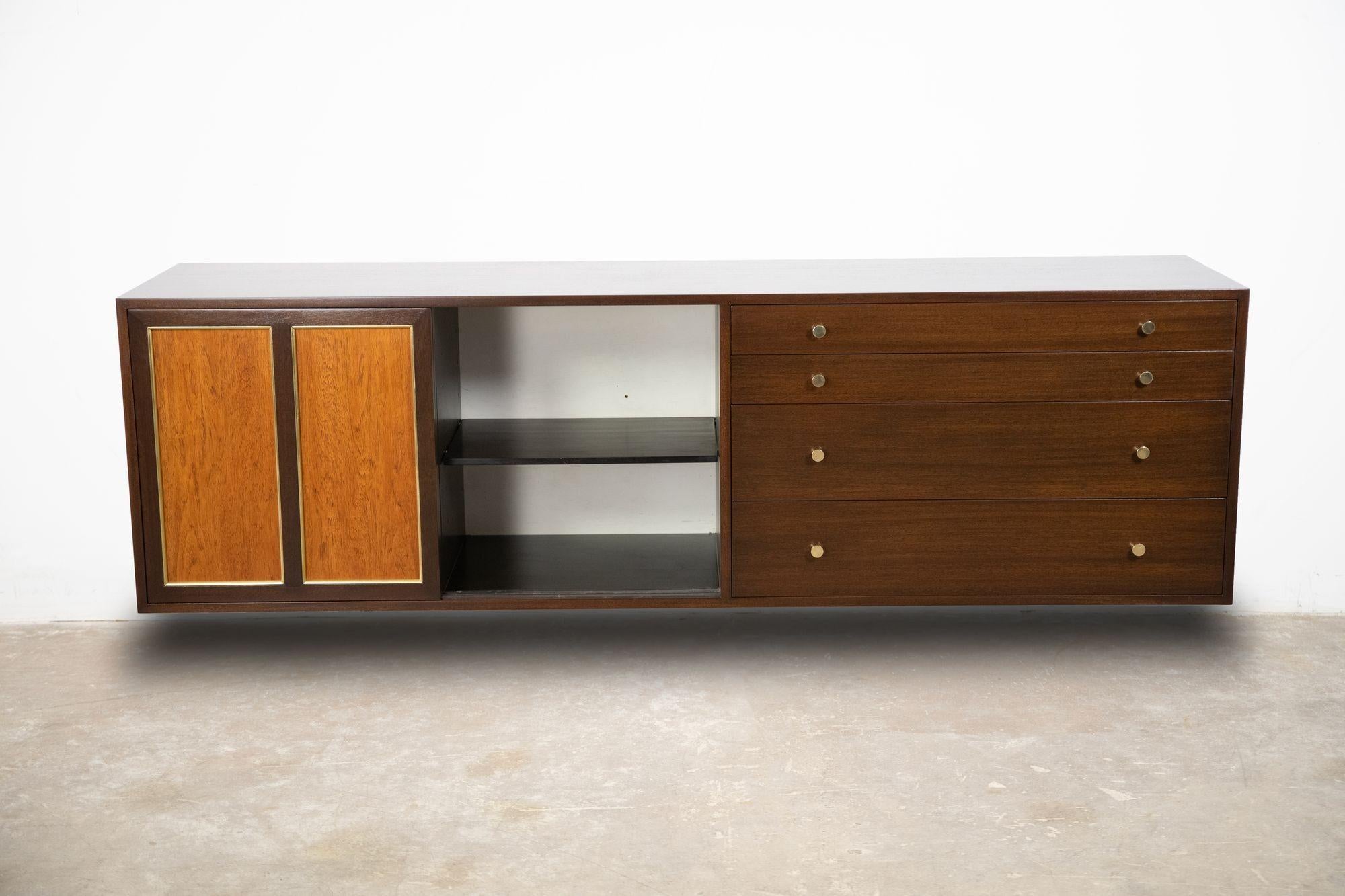 Beautiful four-drawer / sliding door wall mount credenza designed by Harvey Probber. The doors slide open to reveal an adjustable shelf and two slide-out utility drawers, the four drawers have solid brass pulls, and the top drawer for silver. The