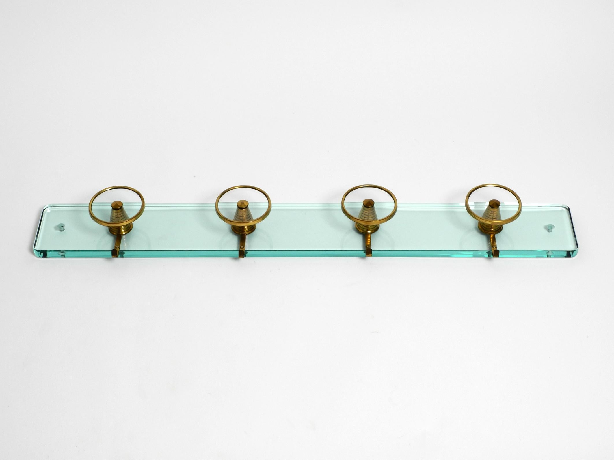 Rare beautiful mid century glass wall coat rack with large glass and brass hanging hooks.
Manufacturer is Fontana Arte. Made in Italy. Great Italian 1950s design.
Very high quality cut glass 2 cm thick.
In the middle, 4 large round glass hooks