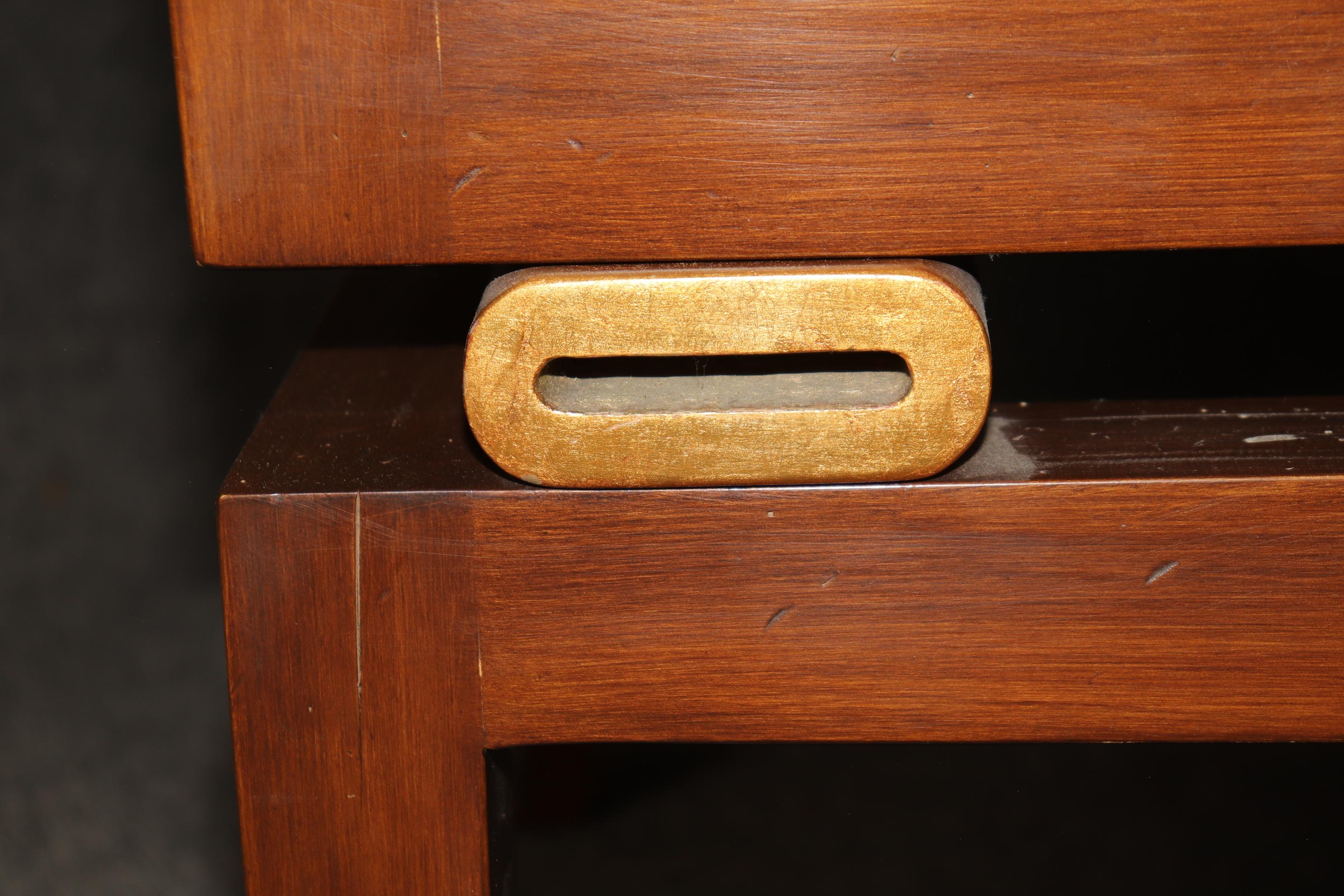This is a superbly designed solid cherry Hollywood Regency, Draper era window bench. The bench features luxurious gold leaf detailed oval shapes to contrast the cherry splayed legs and sleek design. The upholstery is older so expect stains and signs
