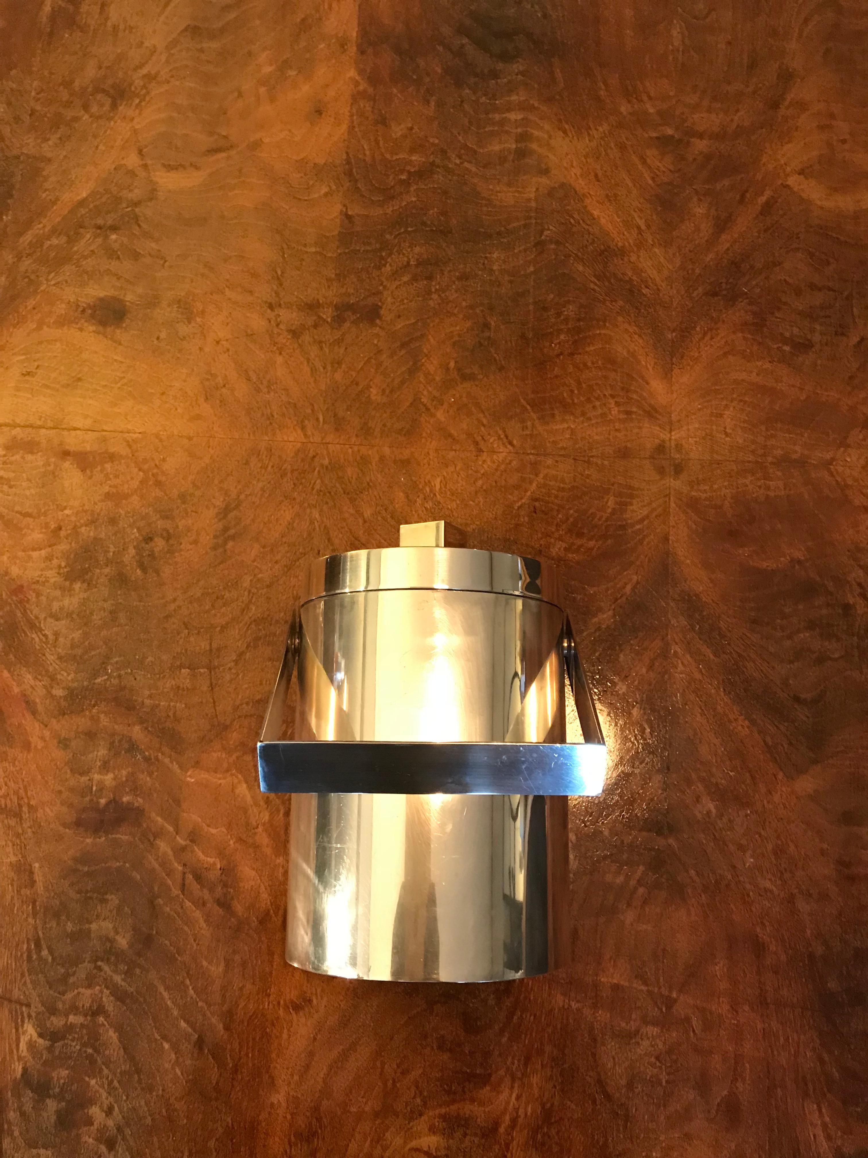 Elegant ice bucket, France, circa 1970s. Very good quality in silvered metal and copper glass inside. Beautiful lines. Geometric style with a square top holder, and great contrast between the copper and silver colors.
Dimensions: diameter 15 cm x