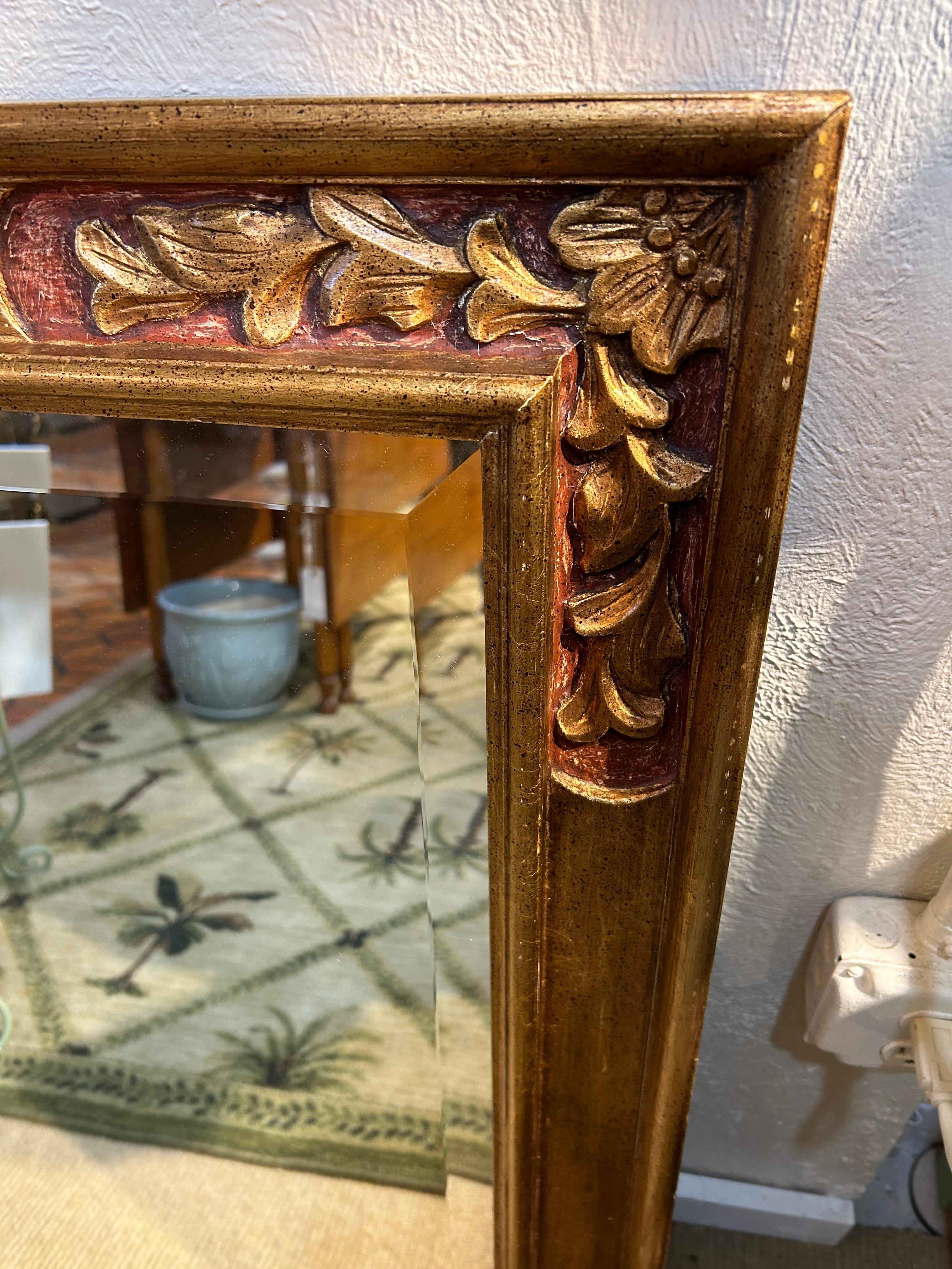 Rich looking with a warm patina, Italian carved wood mirror having gilded decoration in the corners and reddish underpaint.  Bevelled mirror is 31 x 23.25

Maryella