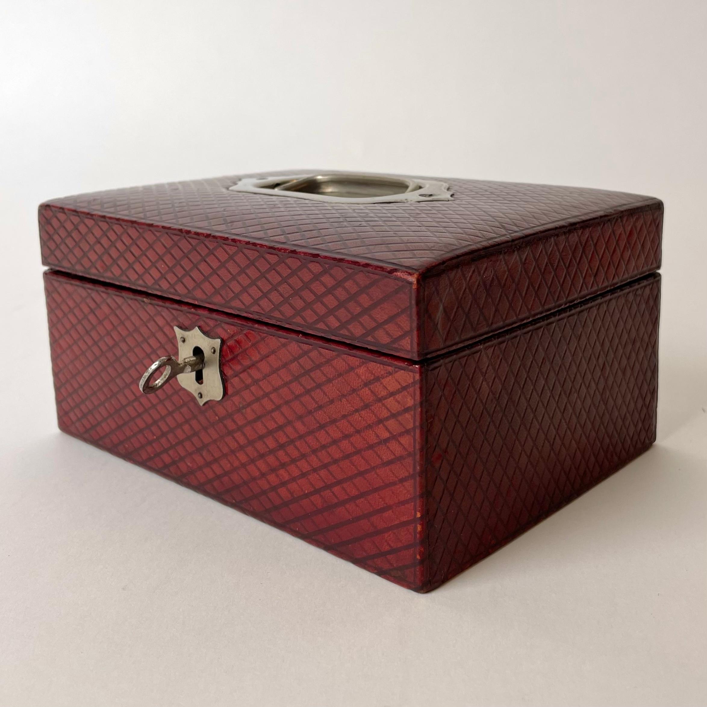 Beautiful Jewelery Box in red leather with an embossed check pattern. Details in nickel and with working lock and key. Probably made in England during the early 20th Century.

Wear consistent with age and use.