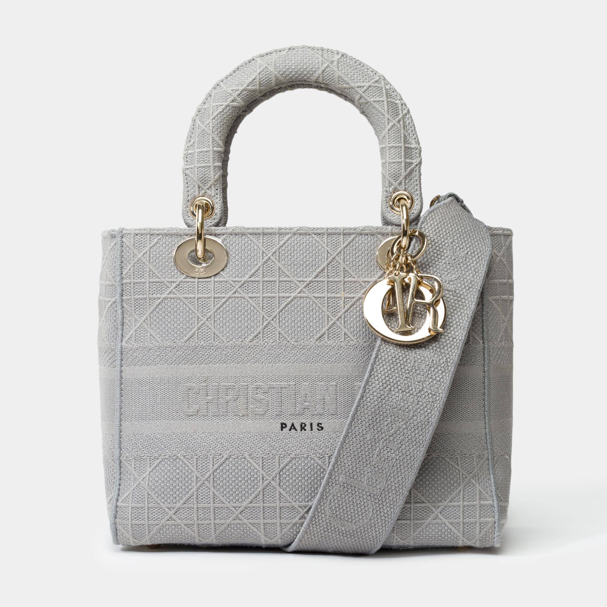 Impresionante e icónico bolso Dior Lady D-Lite de lona cannage gris, con herrajes dorados, asas dobles de lona gris y bandolera de lona gris extraíble para llevarlo en la mano, al hombro o cruzado.

Cierre con solapa
Forro interior de lona gris, con
