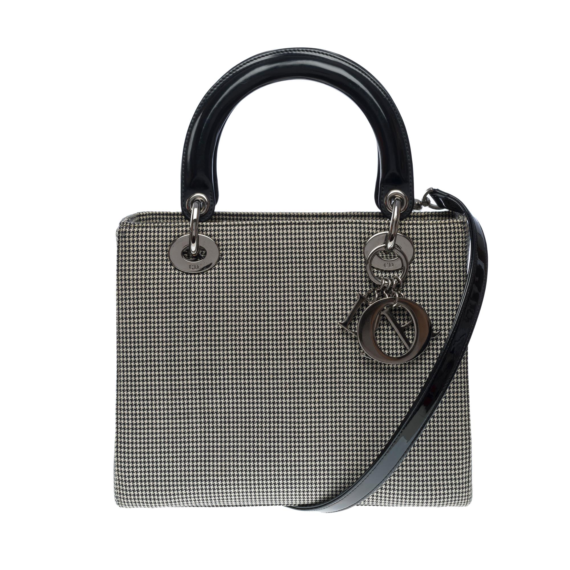 Very chic Lady Dior MM handbag strap in pied-de poule canvas, blackened silver metal hardware, double handle in black patent leather, removable shoulder strap in black patent leather allowing a hand or shoulder or crossbody carry

A zipper
Black