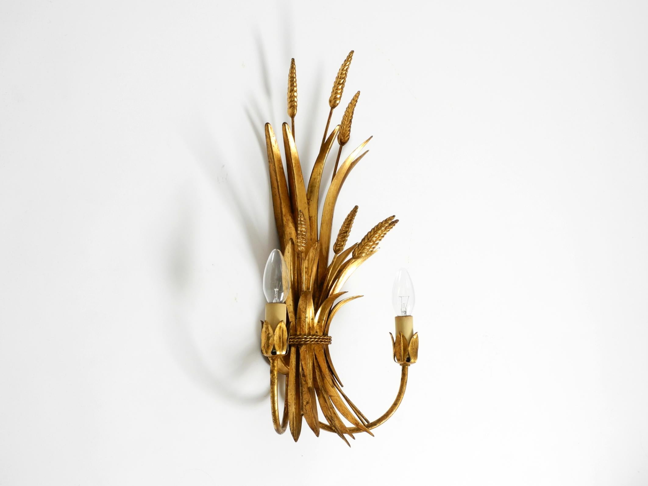 Precioso aplique de metal dorado de dos brazos de la década de 1970, obra de Hans Kögl.
Hans Kögl fue un famoso diseñador de iluminación y mesas. Trabajaba con formas naturales, como hojas de palmera y otras formas vegetales.
Sus diseños se