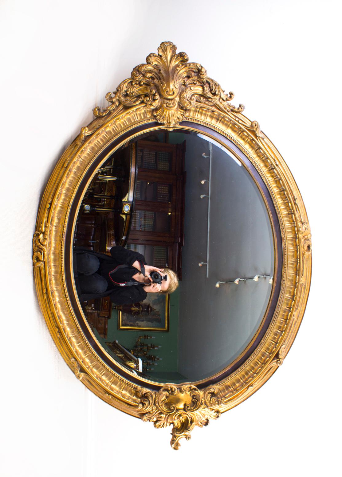 This is a beautiful and highly decorative Vintage Italian Rocco style oval gilt mirror. 

The mirror feature a beautiful deeply carved central shell motif to the top and a cartouche shape plaque on the bottom with decorative acanthus details and a