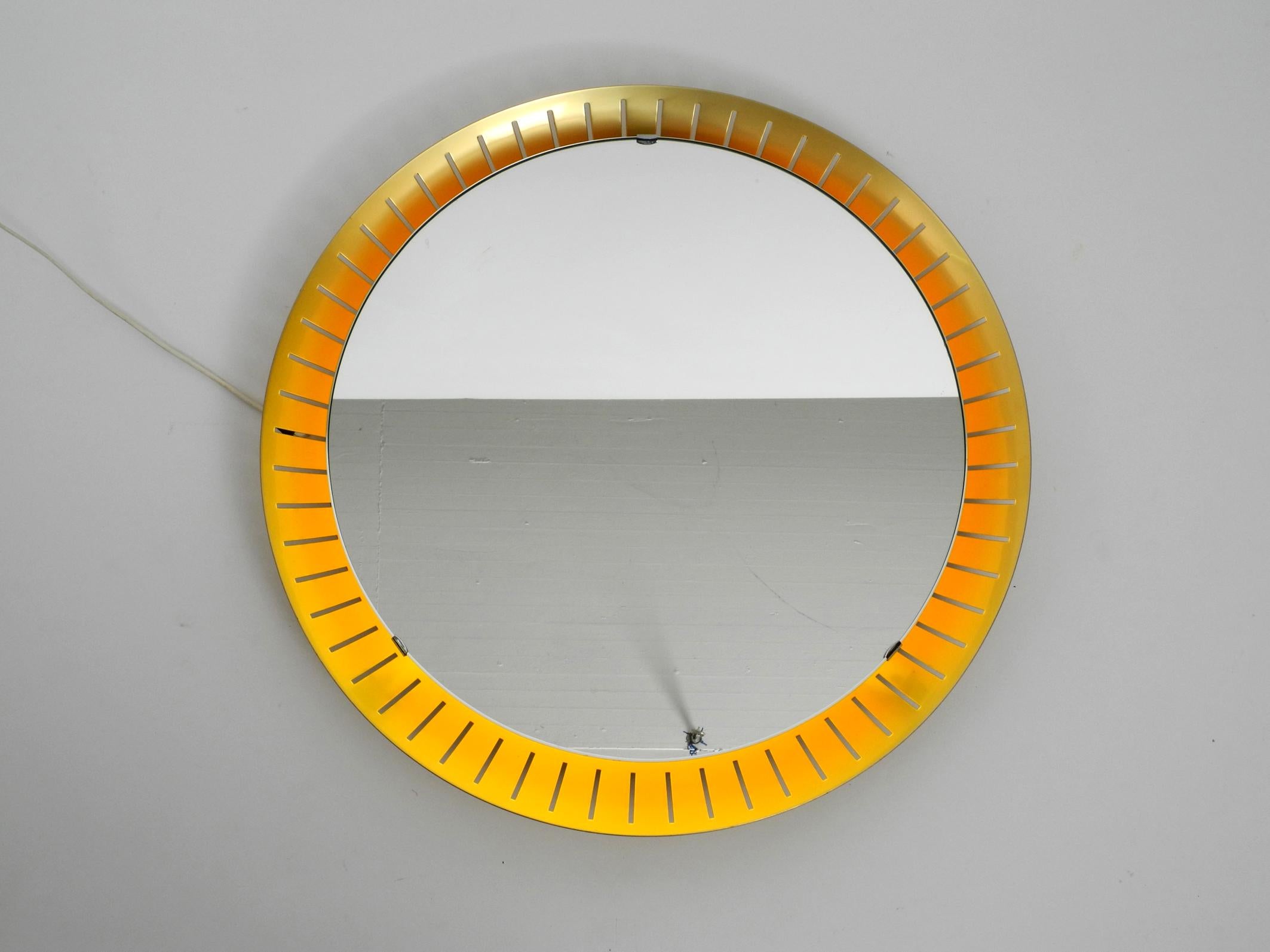 Rare beautiful midcentury illuminated mirror by Hillebrand. Made in Germany.
Aluminum frame is anodised with brass. Beautiful minimalistic 1950s design.
Very thick solid polished mirror glass is hung on the metal frame.
A round neon tube for
