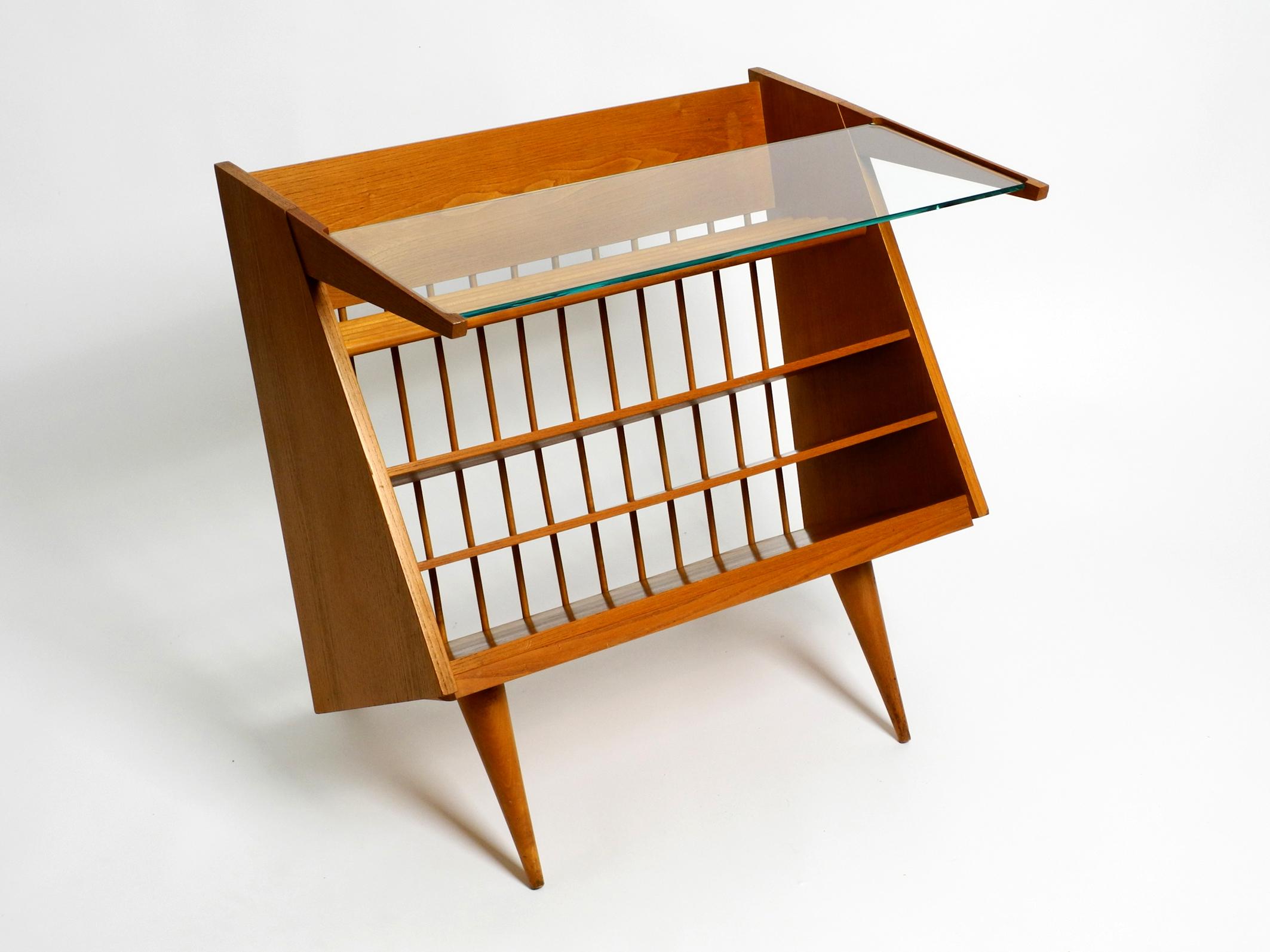 Very rare beautiful large mid-century side table with book and magazine rack made of ash wood and with one glass shelf. Great unusual futuristic 1950s design.
The entire cabinet is made of ash wood.
The detachable shelf is made of thick cut glass.