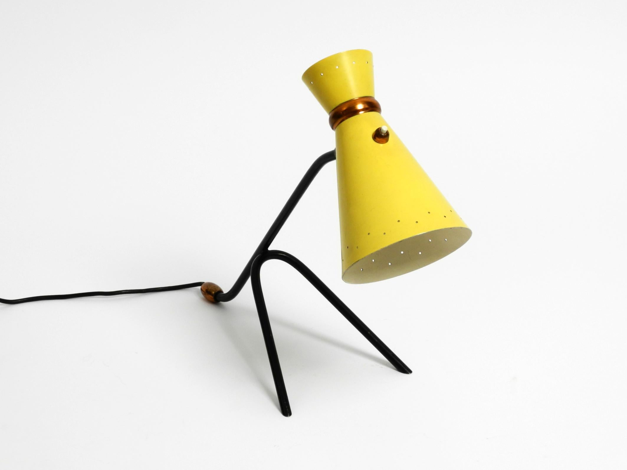 Beautiful large mid-century modern tripod table lamp.
Great 1950s design with the typical colors of the time in yellow and black.
Lampshade in diabolo design with small holes at the edge.
Neck can be rotated continuously in all directions and stays