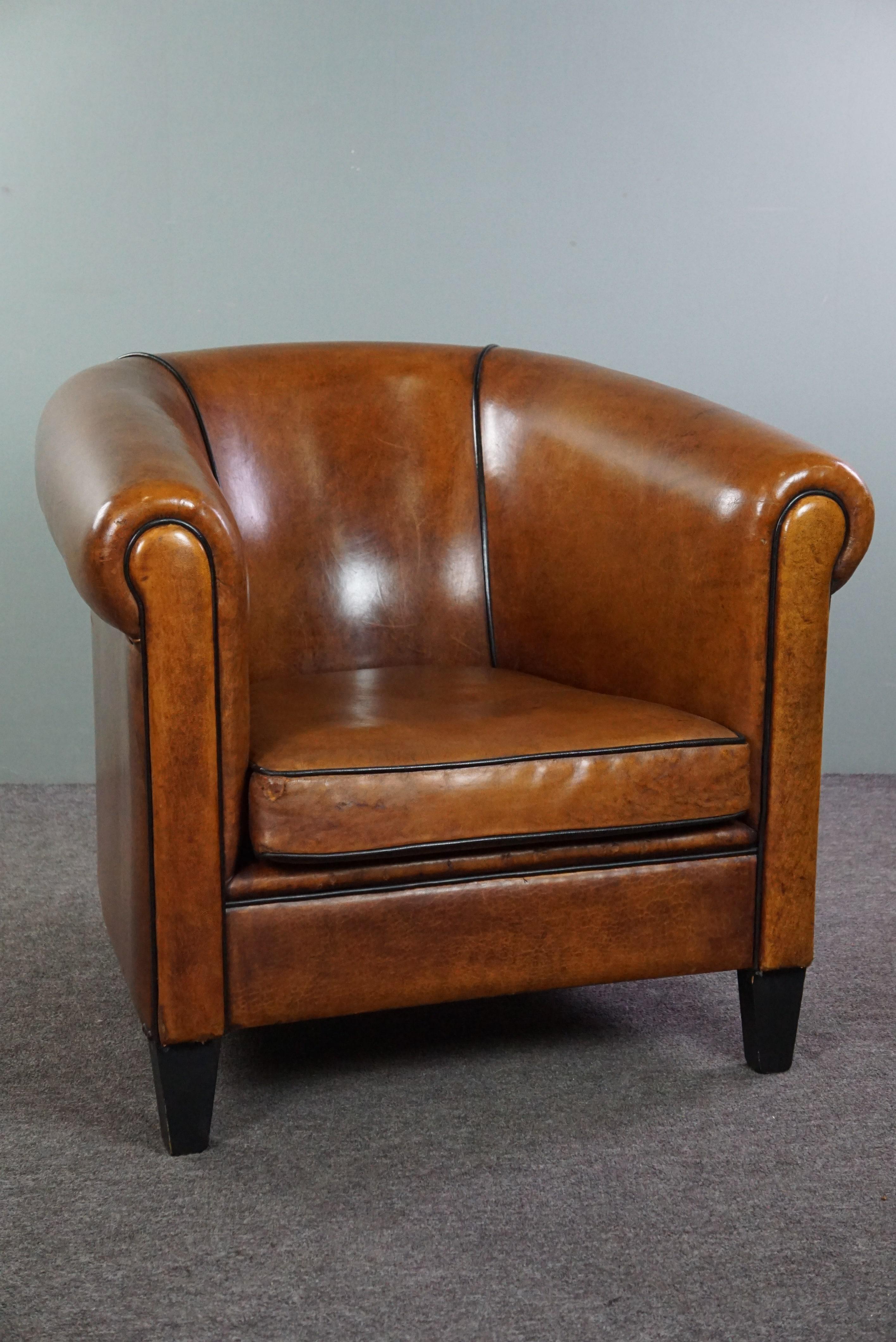 Offered is this beautiful large sheep leather club chair finished with a black piping of very good quality.

This beautiful sheep leather club chair has acquired a beautiful patina through responsible use. Apart from the visible signs of wear, it is