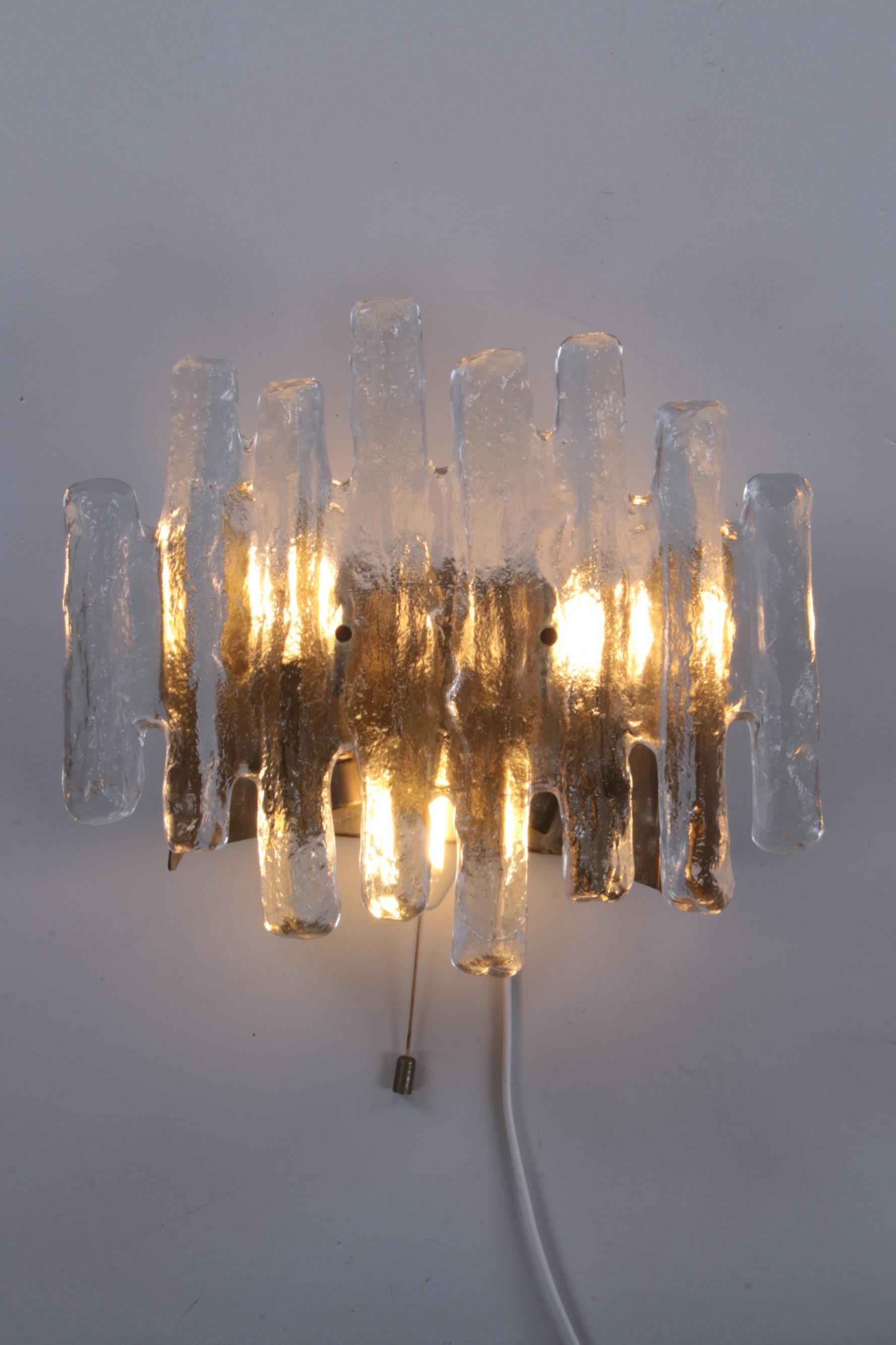 A wall sconce from Kalmar. The sconce has a part of glass. 
The glass is very sparkling. It resembles ice and is called ice glass. 
Very transparent glass with white 