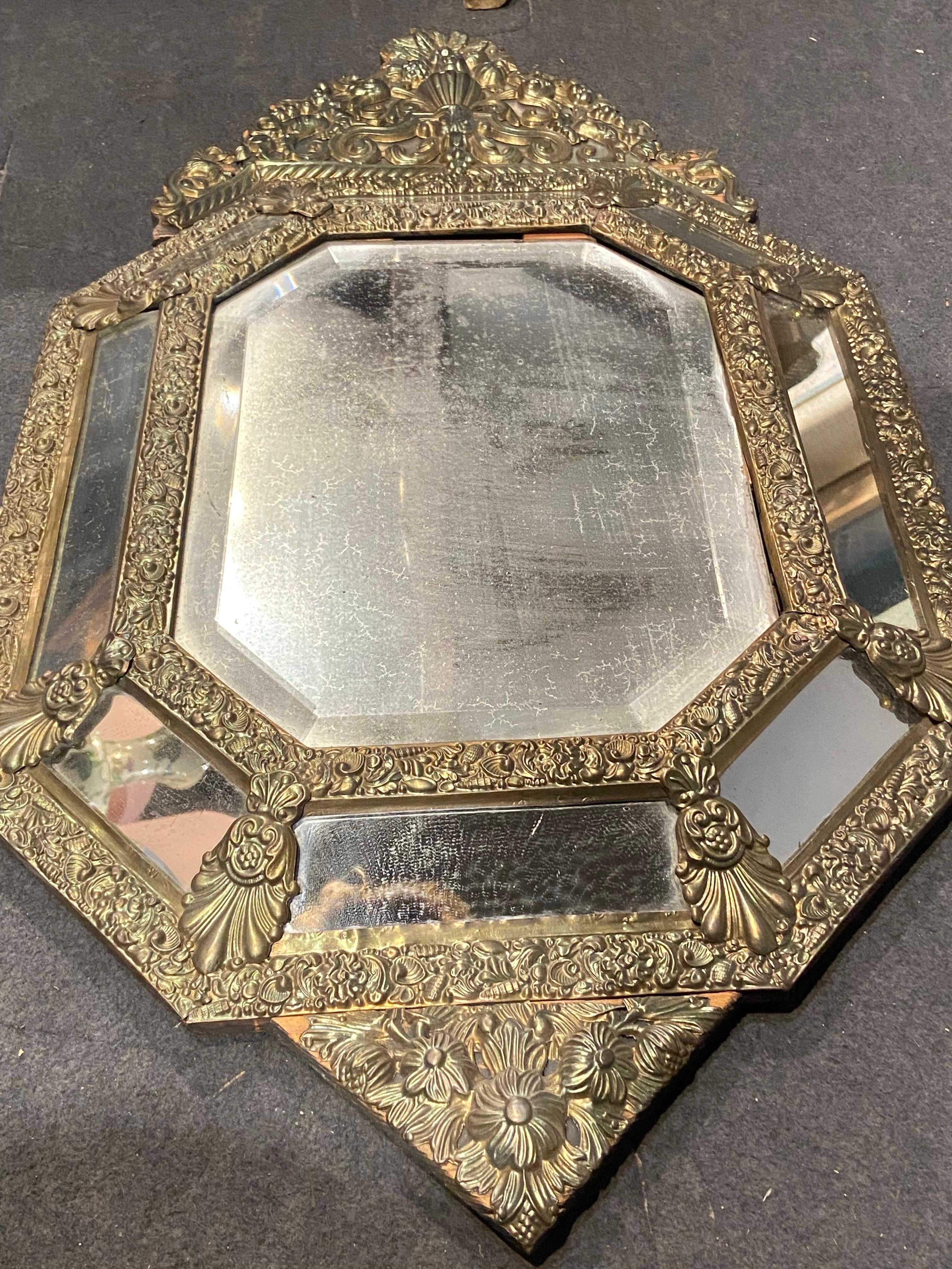 This beautiful mirror frame is made from repoussed brass with all original parts placed over dark oak wood base. The mirror is dated late 19th century and is in a good condition but the glass itself is faded. There were no restorations so