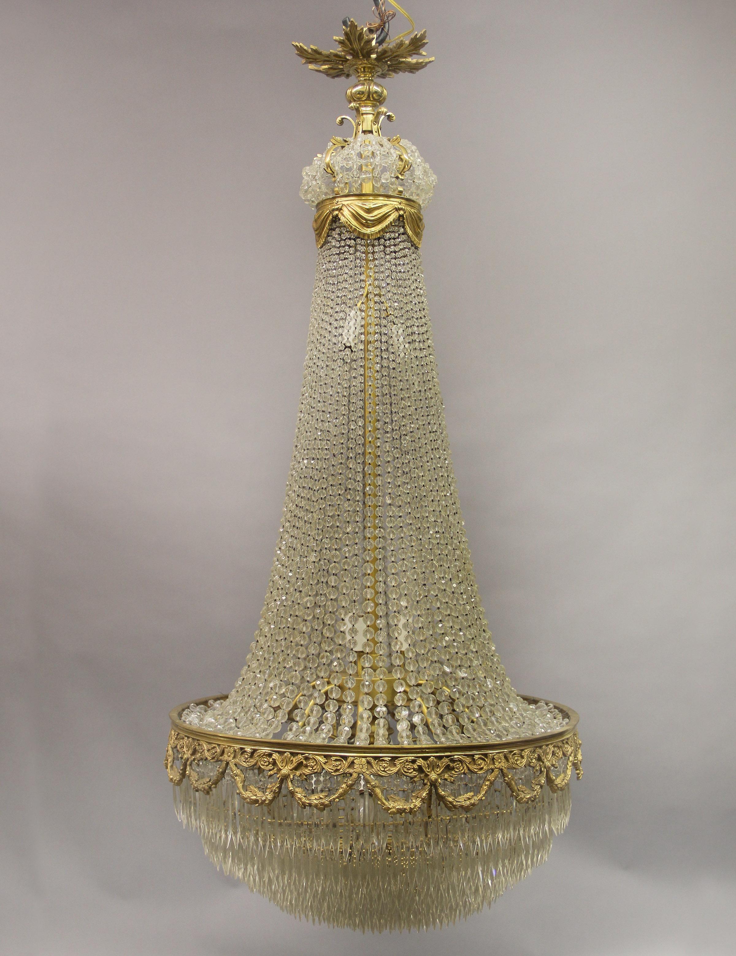 A beautiful late 19th century gilt bronze beaded fourteen light drop crystal chandelier

With a fine bronze and crystal crown shaped dome with curtains, beaded body leading to layered drop crystal, fourteen tiered interior lights.