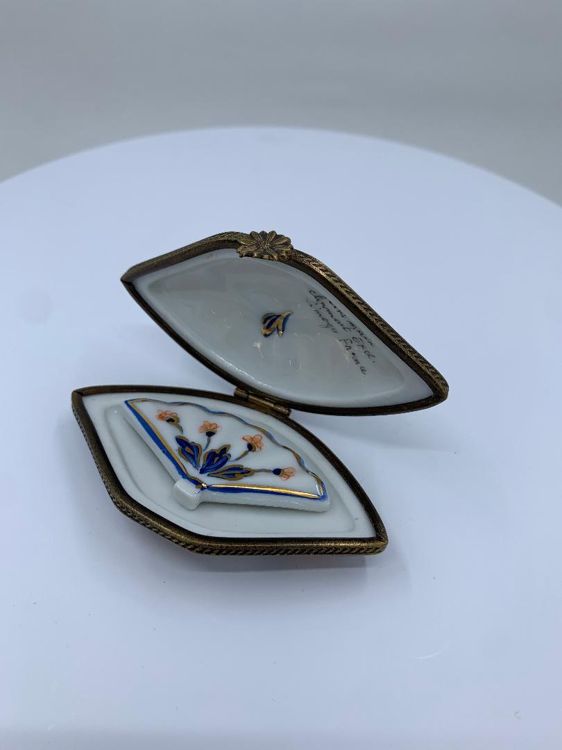 Beautiful Limoges porcelain fan shaped box is handmade and hand painted in rich colors of cobalt blue, iron red and is accented in 24-karat gold. Fan opens to reveal another removable fan inside. Box features antiqued gold gilt metal fittings and