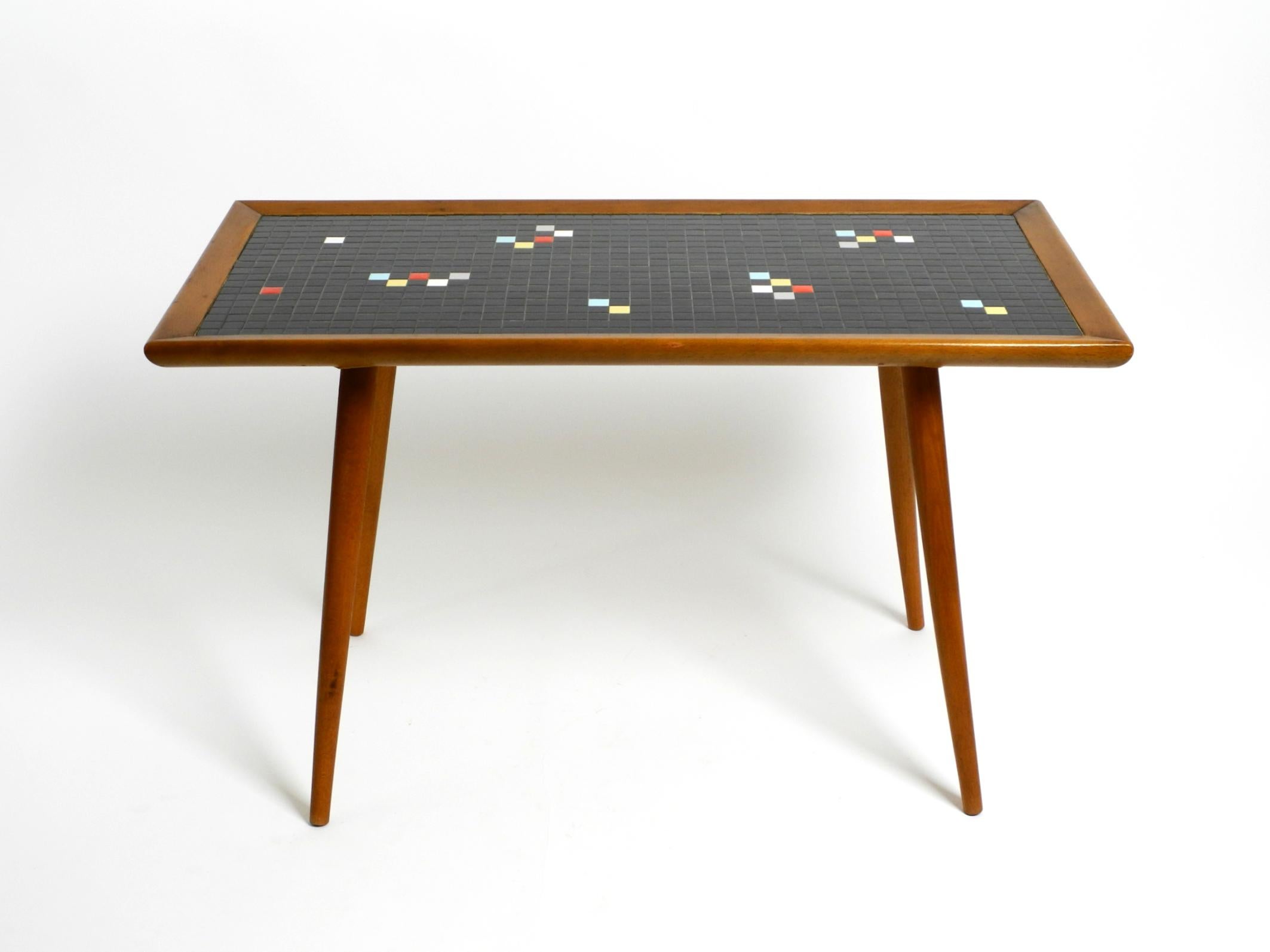 Extraordinaire table rectangulaire en noyer pour canapé ou table d'appoint du milieu du siècle dernier.
Surface avec des pierres de mosaïque carrées noires en céramique.
Quelques pierres colorées sont disposées dans un motif abstrait.
Design/One