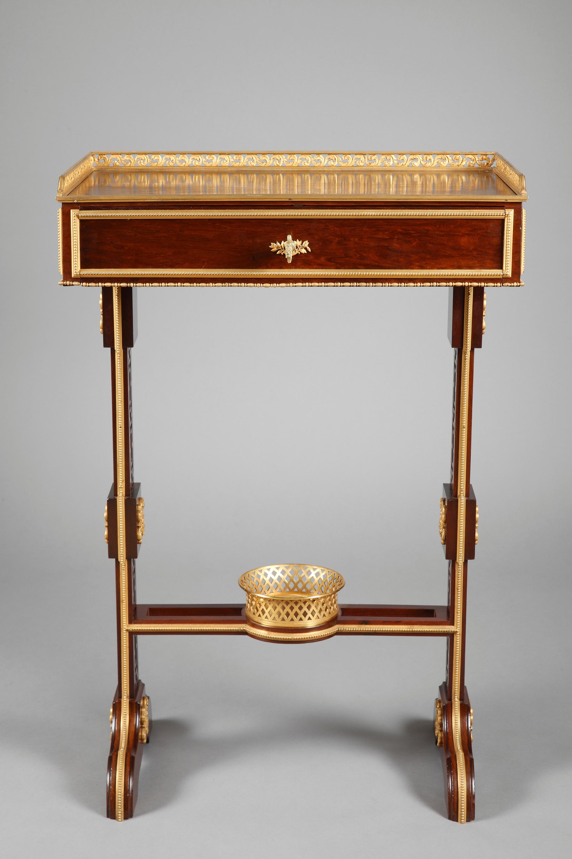 Beautiful Louis XVI style wooden writing table. The rectangular top, surrounded on three sides by a fine pierced and gilt-bronze frieze, above a drawer whose front forms a flap opening by a clever mechanism, revealing an elegant brown leathered