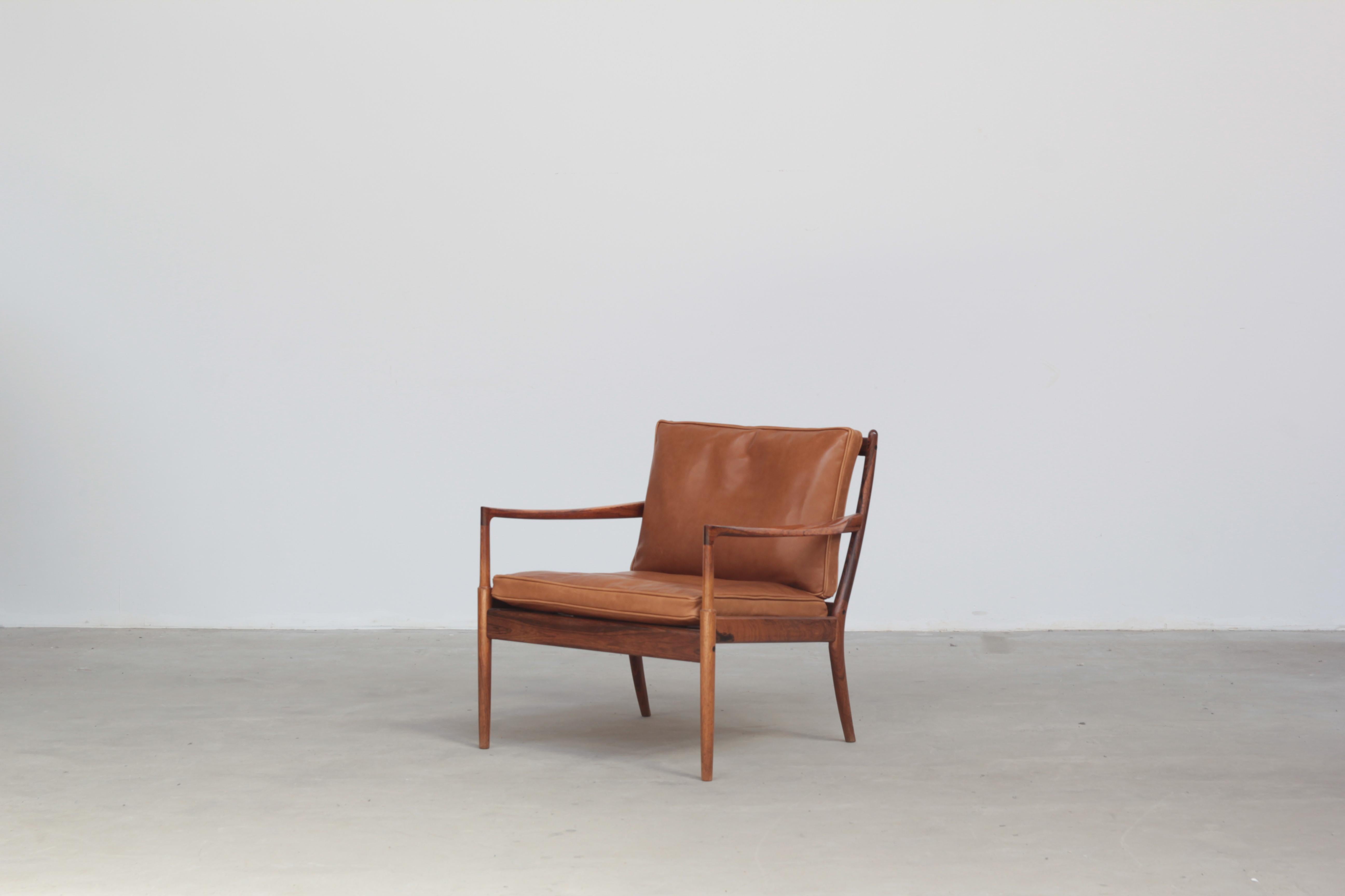 The lounge chair designed by Ib Kofod-Larsen in 1958 for OPE Mobler is a stunning example of mid-century Danish design. The chair is crafted from exquisite rosewood, which gives it a warm and luxurious feel. The brown cognac leather cushions are in