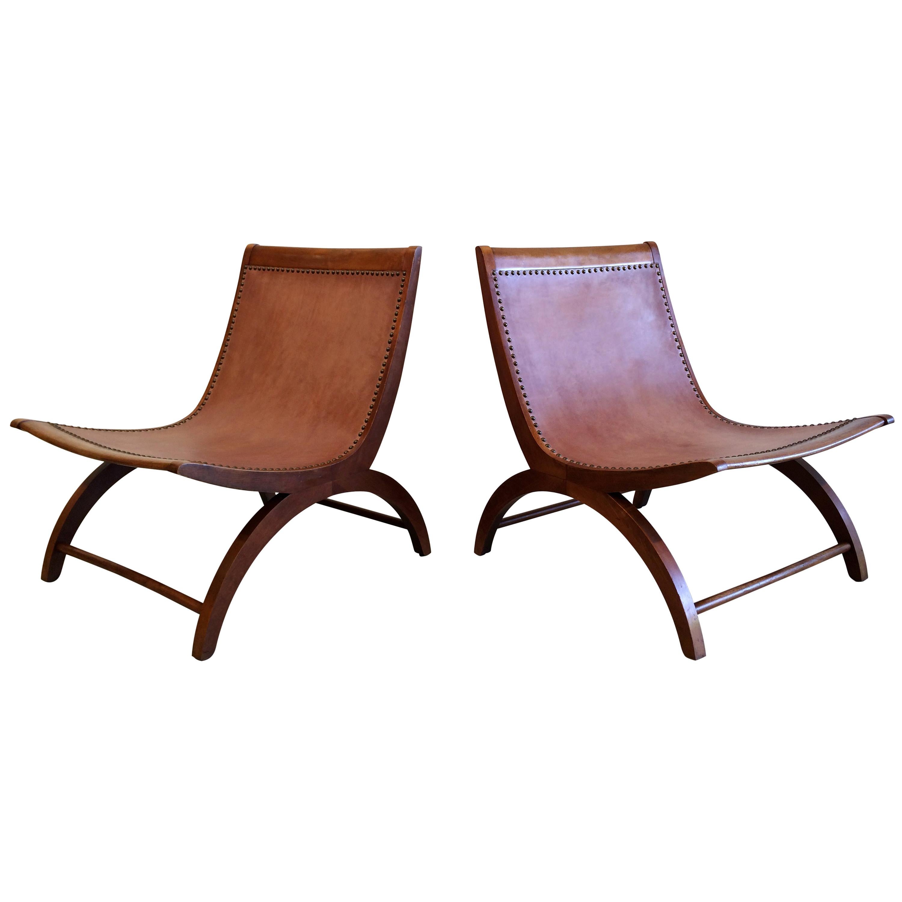 Rare pair of wooden lounge chairs with saddle leather seats.
