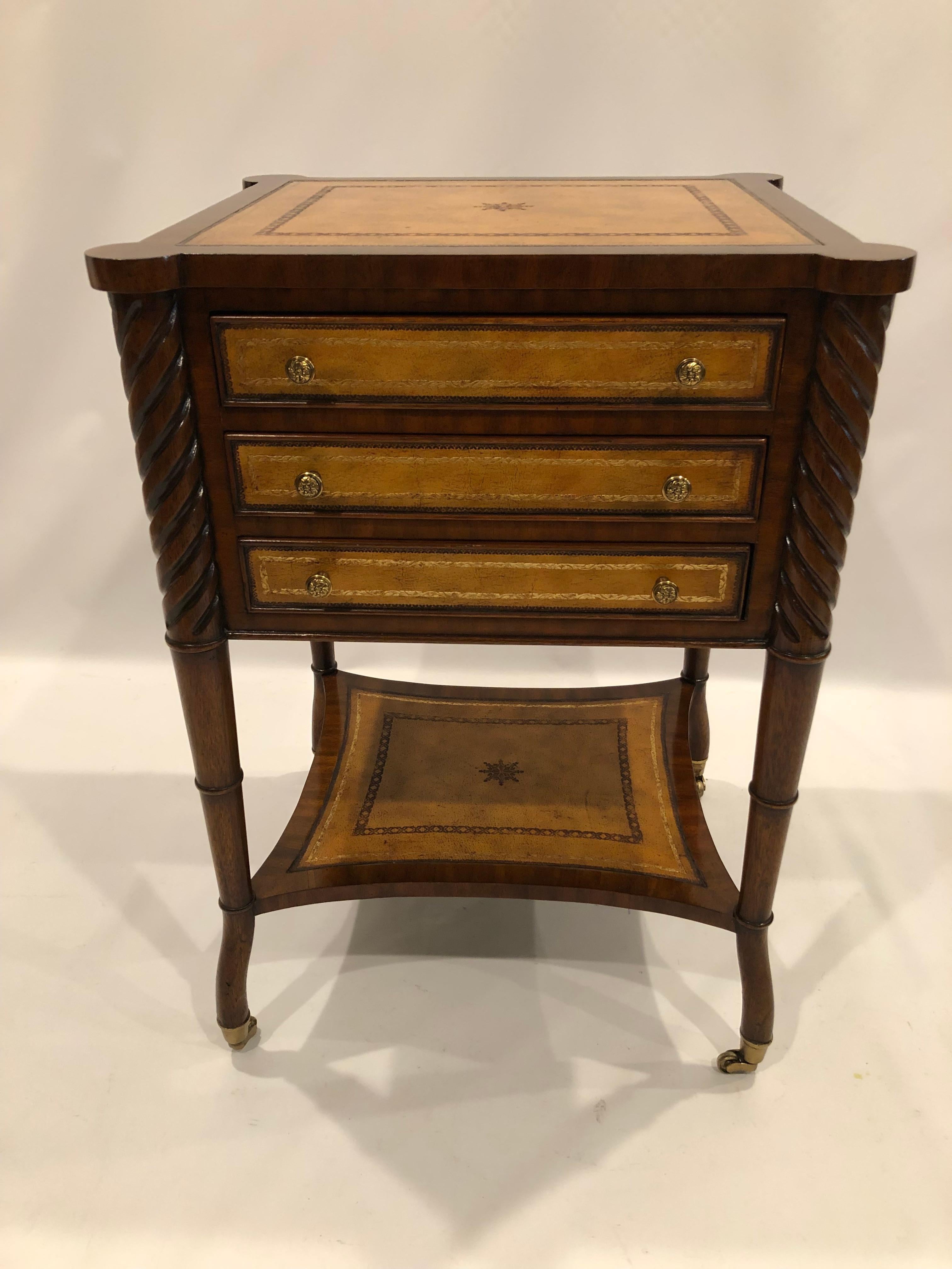 Incredibly made embossed leather and mahogany side table or chest having 3 drawers and carved wood twisted corners. Leather is also on all sides and lower tier. Elegant legs terminate in brass casters.