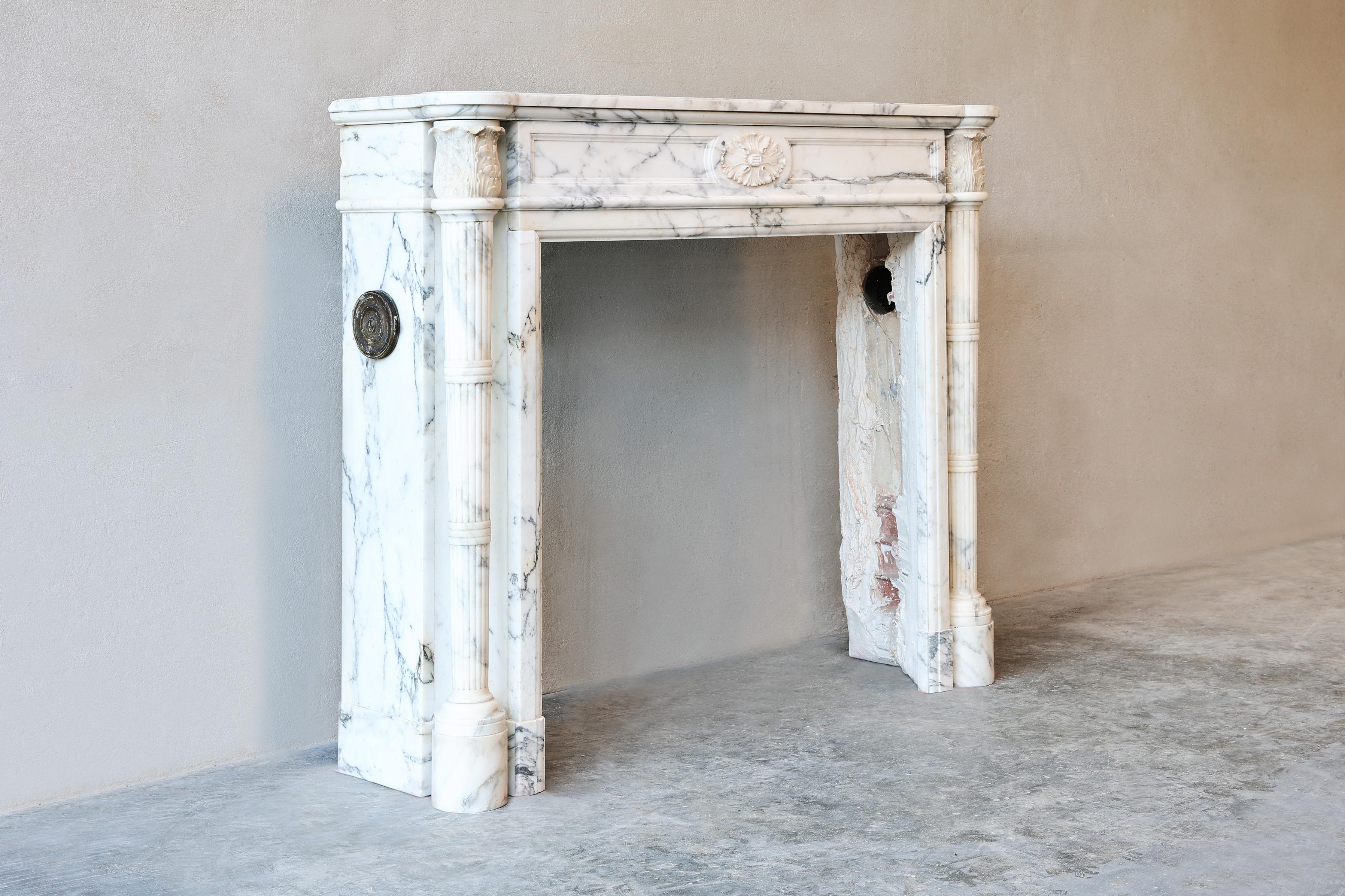 Beautiful antique fireplace of Arabescato marble from the 19th century in style of Louis XVI. This fireplace has a beautiful ornament in the middle of the front part and at the top of the legs. The flutes on the legs also gives this fireplace a nice