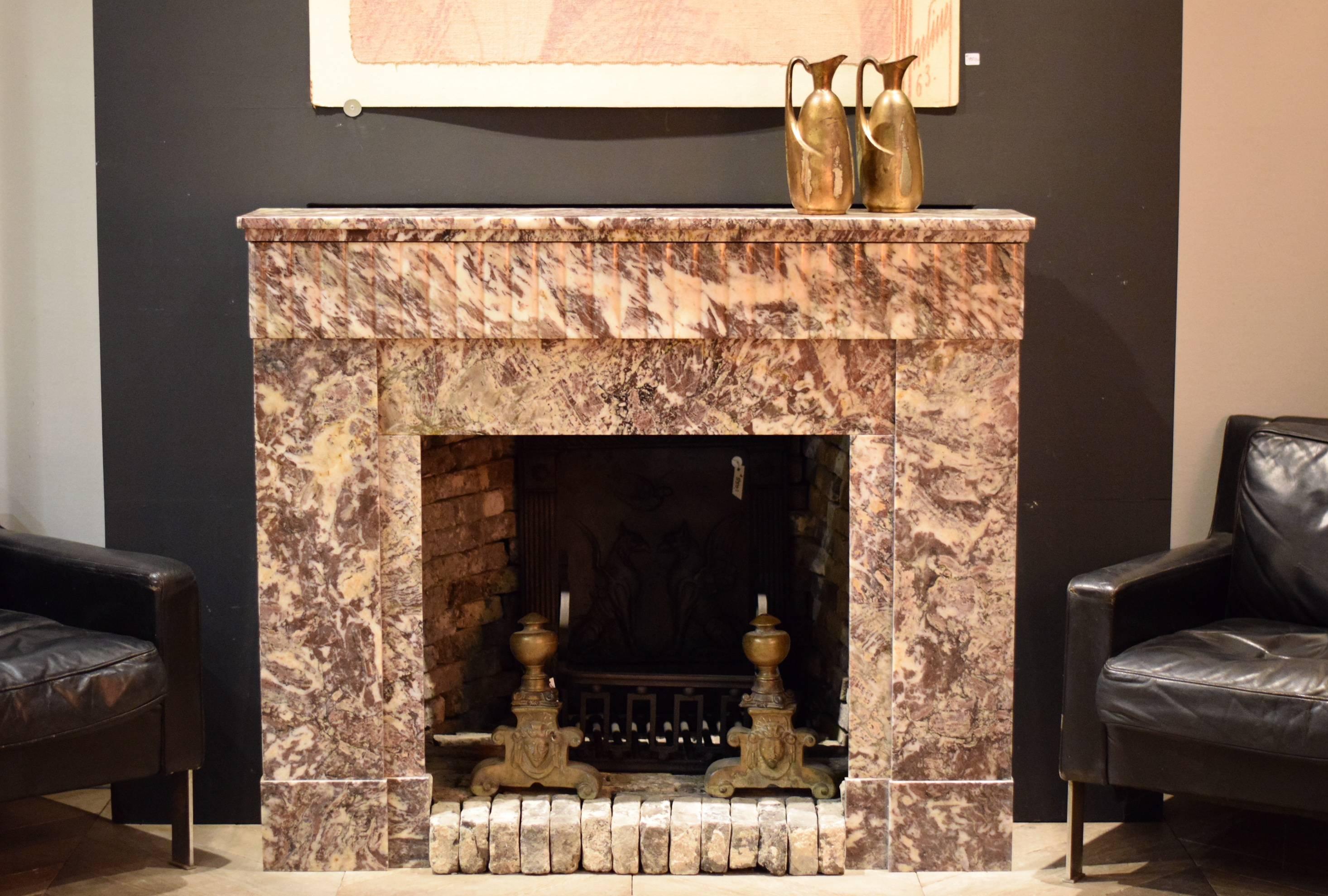 Beautiful Art Deco fireplace made in the 1920s in France. The fireplace is made from a marble with veins and shades of red, grey, white and yellow. 

The fireplace is in a great condition. However there is an old restoration visible in the top (as