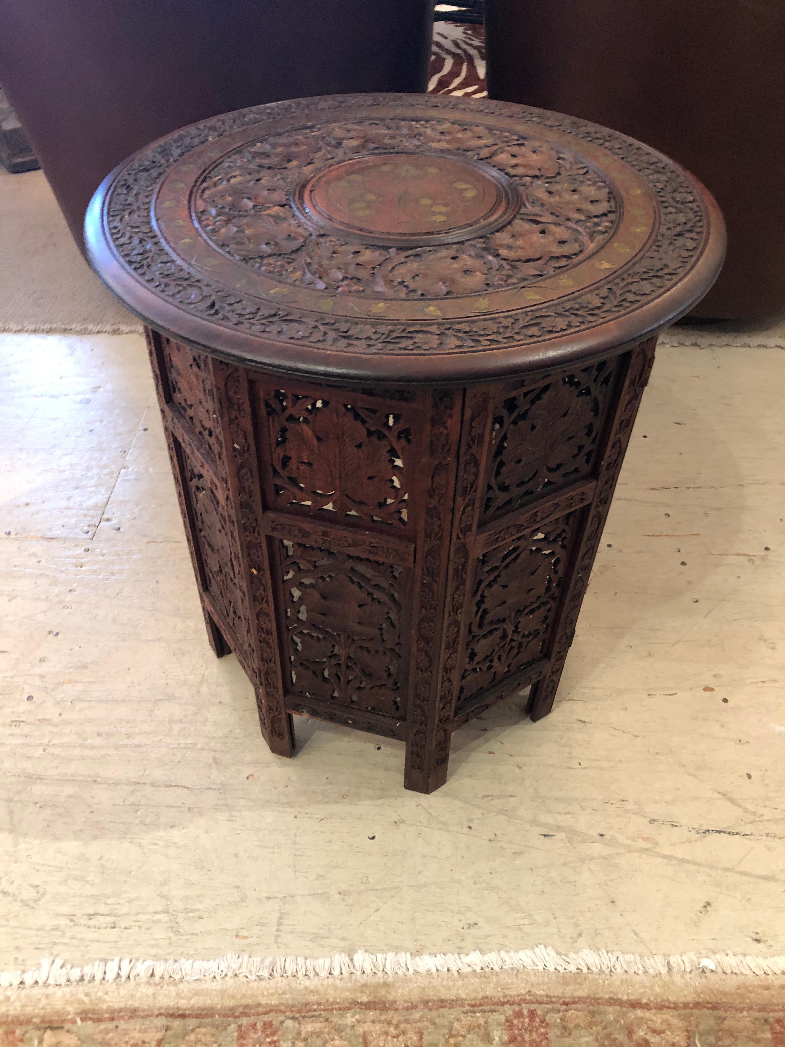 Intricately carved Moorish round end table with leafy foliage decoration and lovely inlay.
Base is octagonal carved wood and accordians flat for shipping, top is removable.