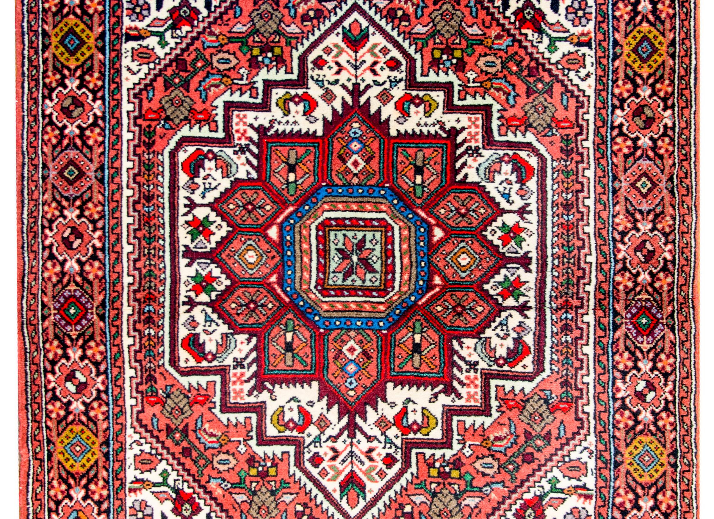 A beautiful mid-20th century Persian Bidjar rug with a large twelve-lobed floral crimson medallion on field of flowers on a white background. The border in fantastic with a large-scale stylized floral and vine patterned central stripe flanked by