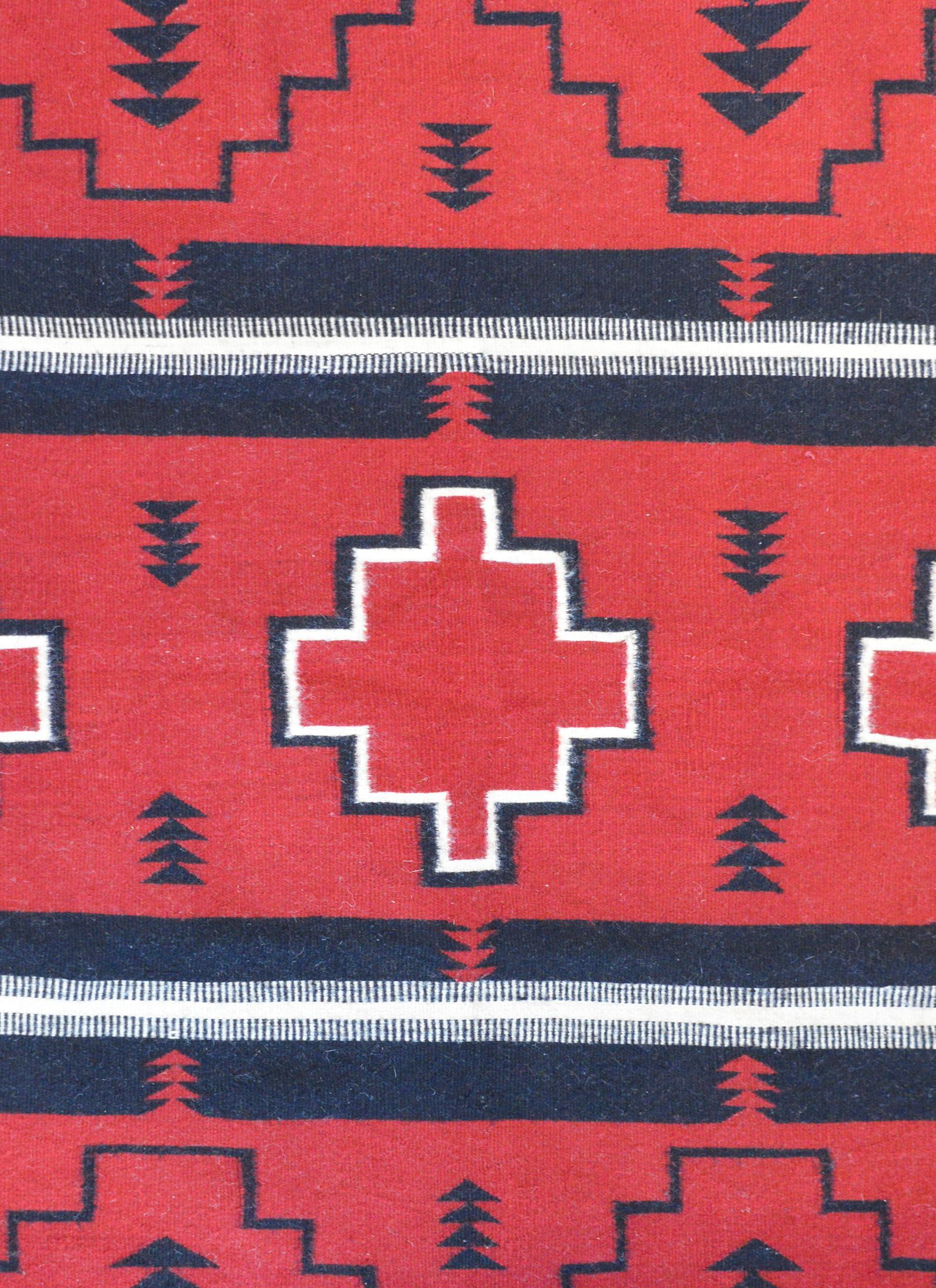 A beautiful mid-20th century Navajo rug with a bold crimson, black, and white pattern with a large diamond in the center amidst a field of small black arrows.