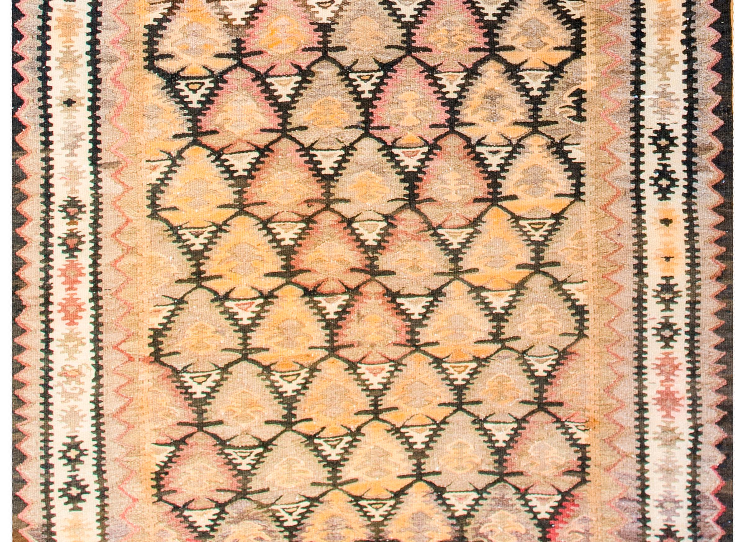 A beautiful mid-20th century Persian Qazvin Kilim rug with an all-over tree-of-life pattern woven with orange, lilac, crimson, and natural wool colored vegetable dyed wool. The border is complex, with three distinct geometric patterns, with the