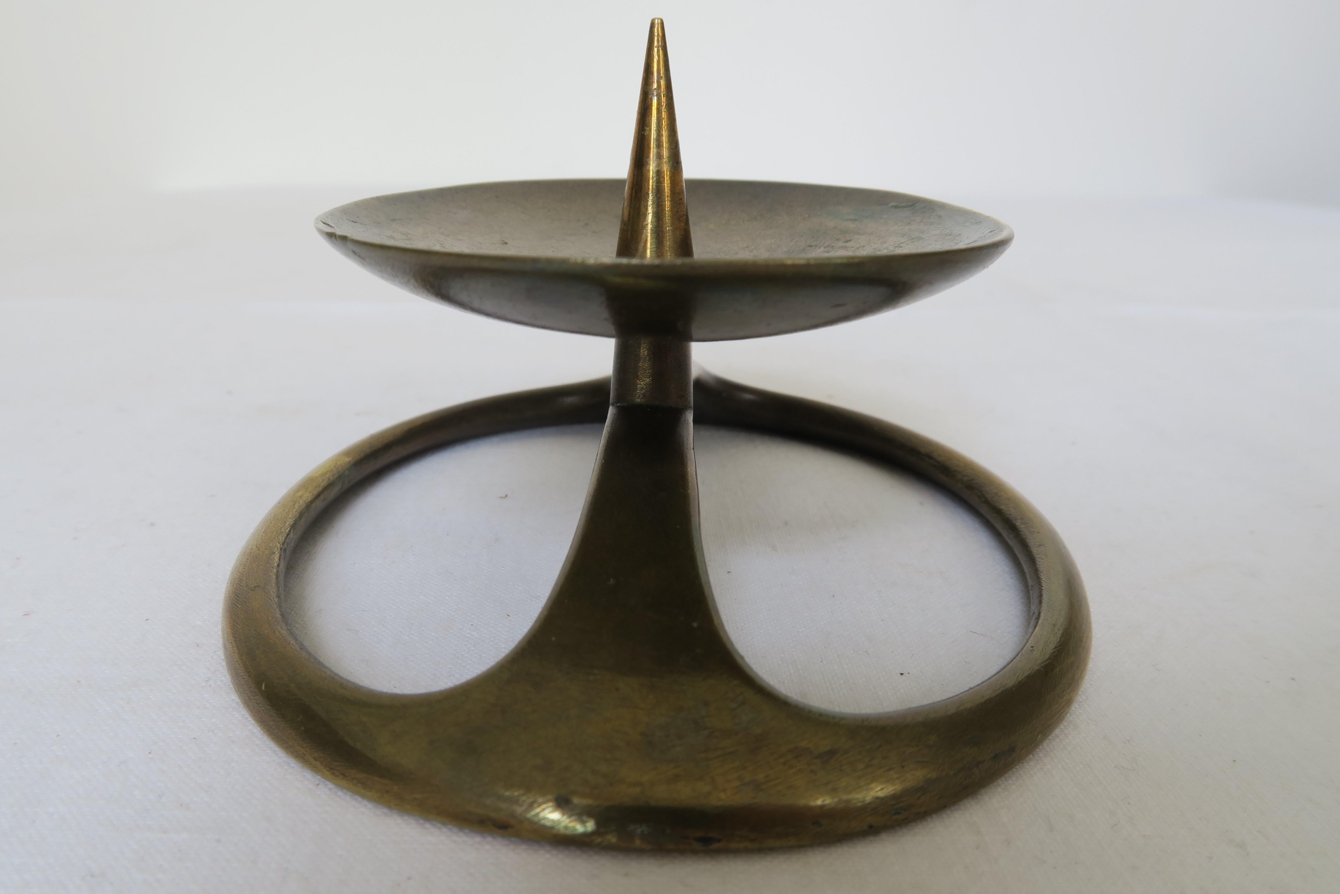 The item for sale is a unique piece of Mid-Century Modern design. The candlestick was produced in the Austrian workshops of renowned Bauhaus-influenced designer Carl Auböck. It consists of brass and displays some deliciously smooth curves and