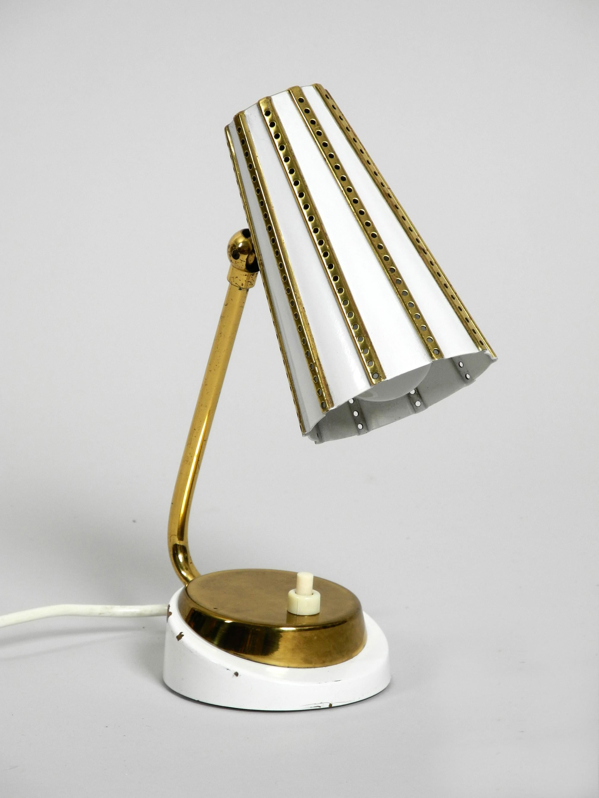 Beautiful midcentury brass table bedside lamp with perforated metal shade.
Very nice design of the 1950s with great patina.
Shade can be continuously turned up and down.
The whole lamp is made of brass and is painted partly in white.
100%
