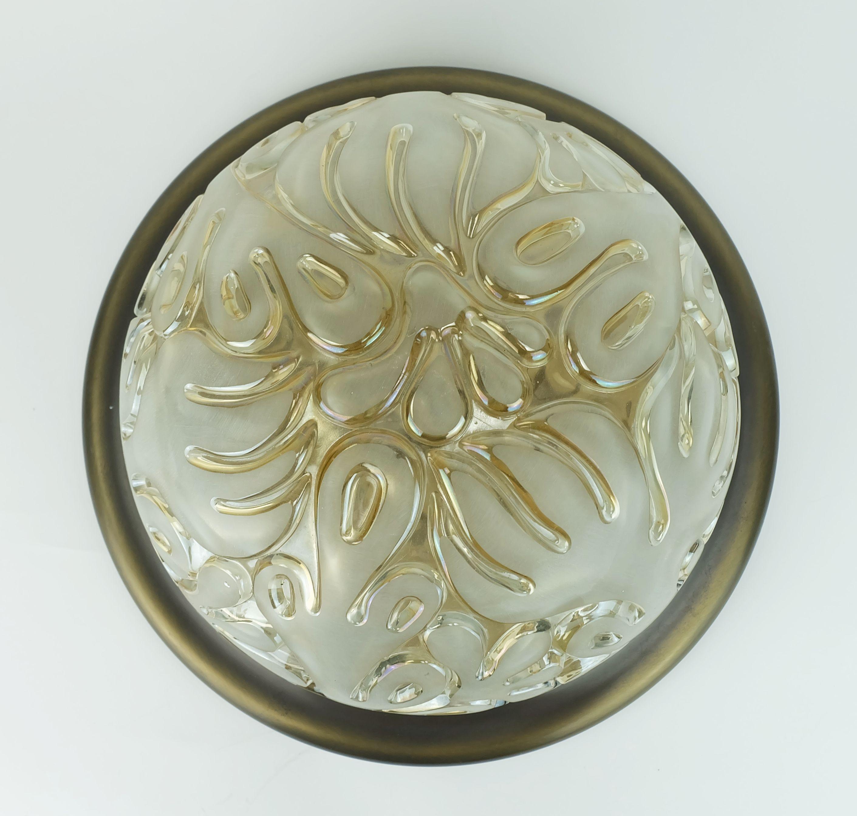 Una lámpara de techo muy bonita de los años 70. La pantalla es de cristal transparente de color ámbar claro con decoración floral grabada en las superficies elevadas y transparente en los huecos. El oro translúcido de la placa base crea bellos