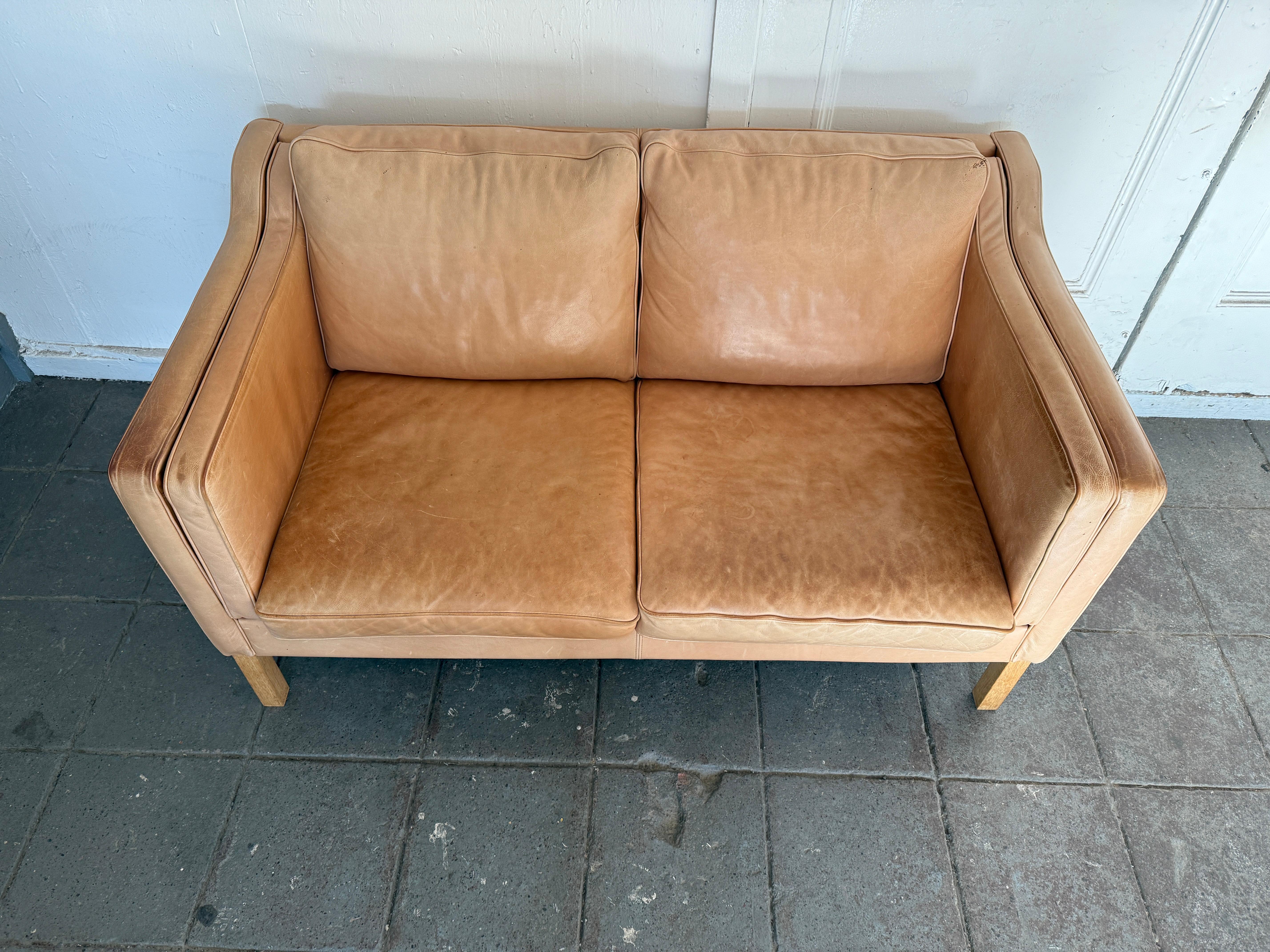 Great mid century Danish modern tan leather 2 seat loveseat sofa with Square white oak legs. Style of Børge Mogensen. Beautiful thick tan leather is soft and shows signs of use but broken in nicely. Tan leather shows fading, patina and scuffs from