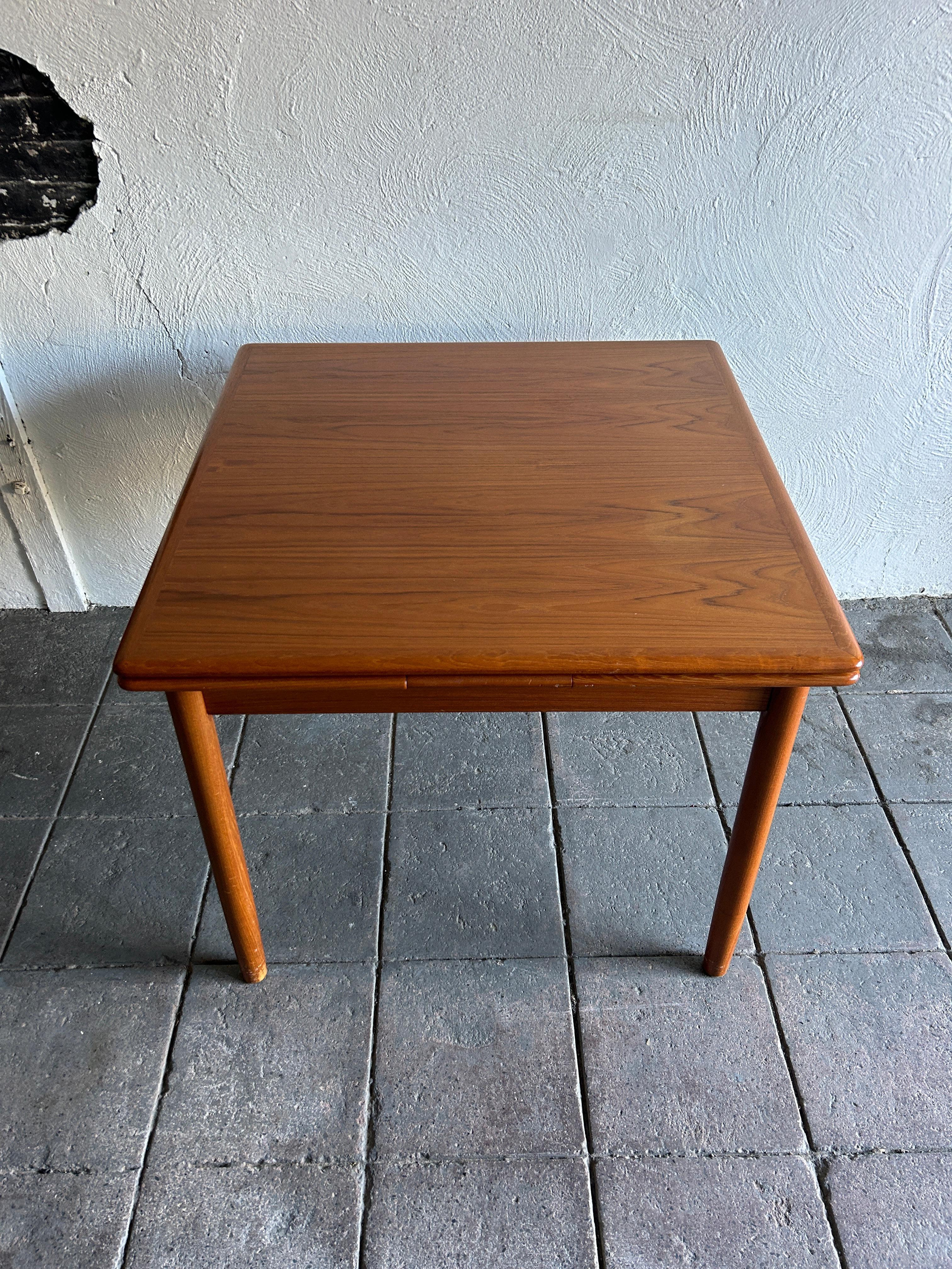 Mid century Danish Modern teak small square extension dining table Beautiful teak table that extends with (2) nesting pull out leaves. The leaves have carved handles under leaf to pull out. Solid teak round legs with a square table top 34” x 34” x