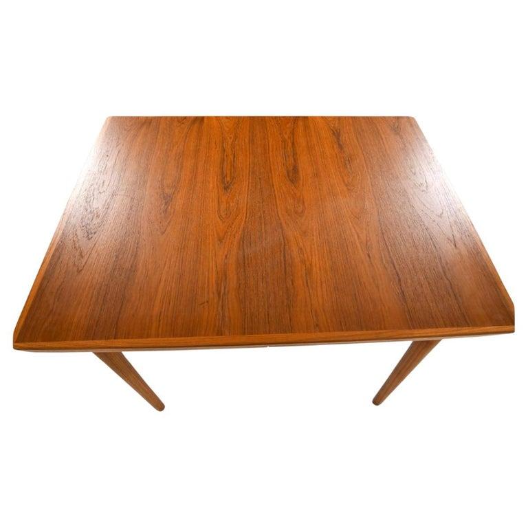 Table de salle à manger carrée en teck du milieu du siècle dernier Magnifique table en teck qui se rallonge avec (2) feuilles gigognes escamotables. Les feuilles sont munies de poignées sculptées sous la feuille pour les retirer. Pieds en teck