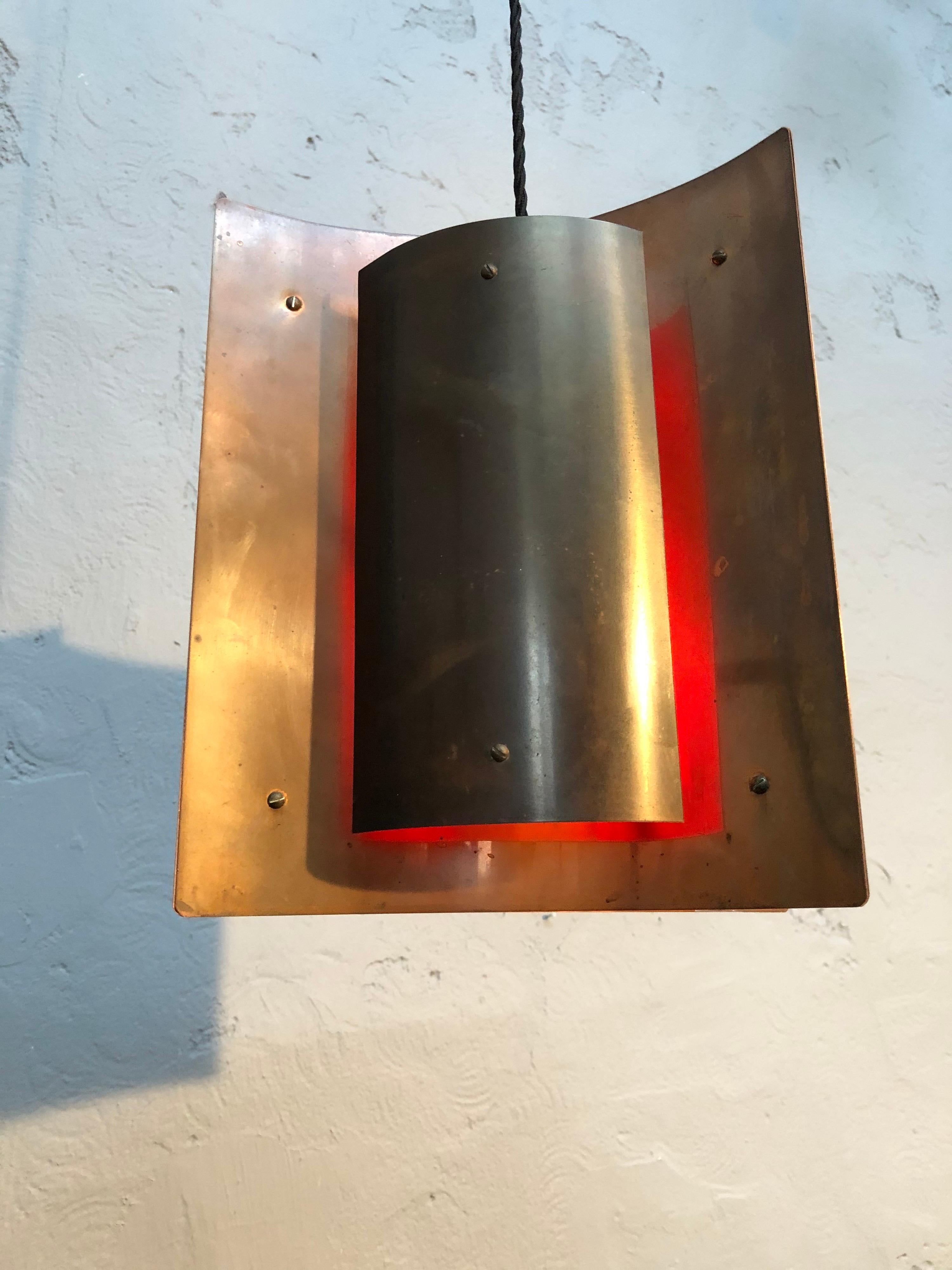 Schöne dänische Pendel-Deckenlampe aus der Mitte des Jahrhunderts in Kupfer. 
Ein 4-seitiger Anhänger, der aus zusammenpassenden Kupferstücken besteht, mit einem Kupferdefusor in der Mitte, der auf der Innenseite rot lackiert ist, um dem Anhänger
