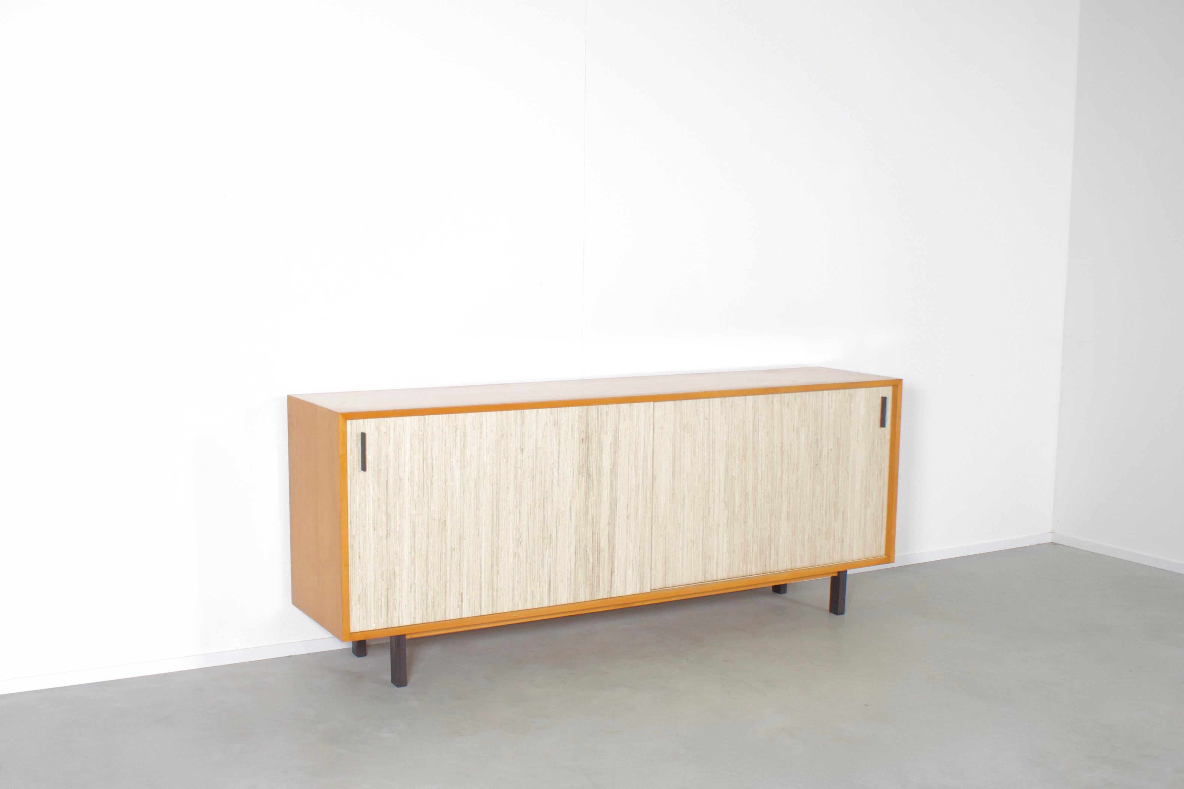 Very well made midcentury sideboard in very good condition.

Made in Italy in the 1960s

This clean-lined sideboard is made of beautiful maple wood.

The large sliding-doors are covered in Seagrass and are equipped with black metal