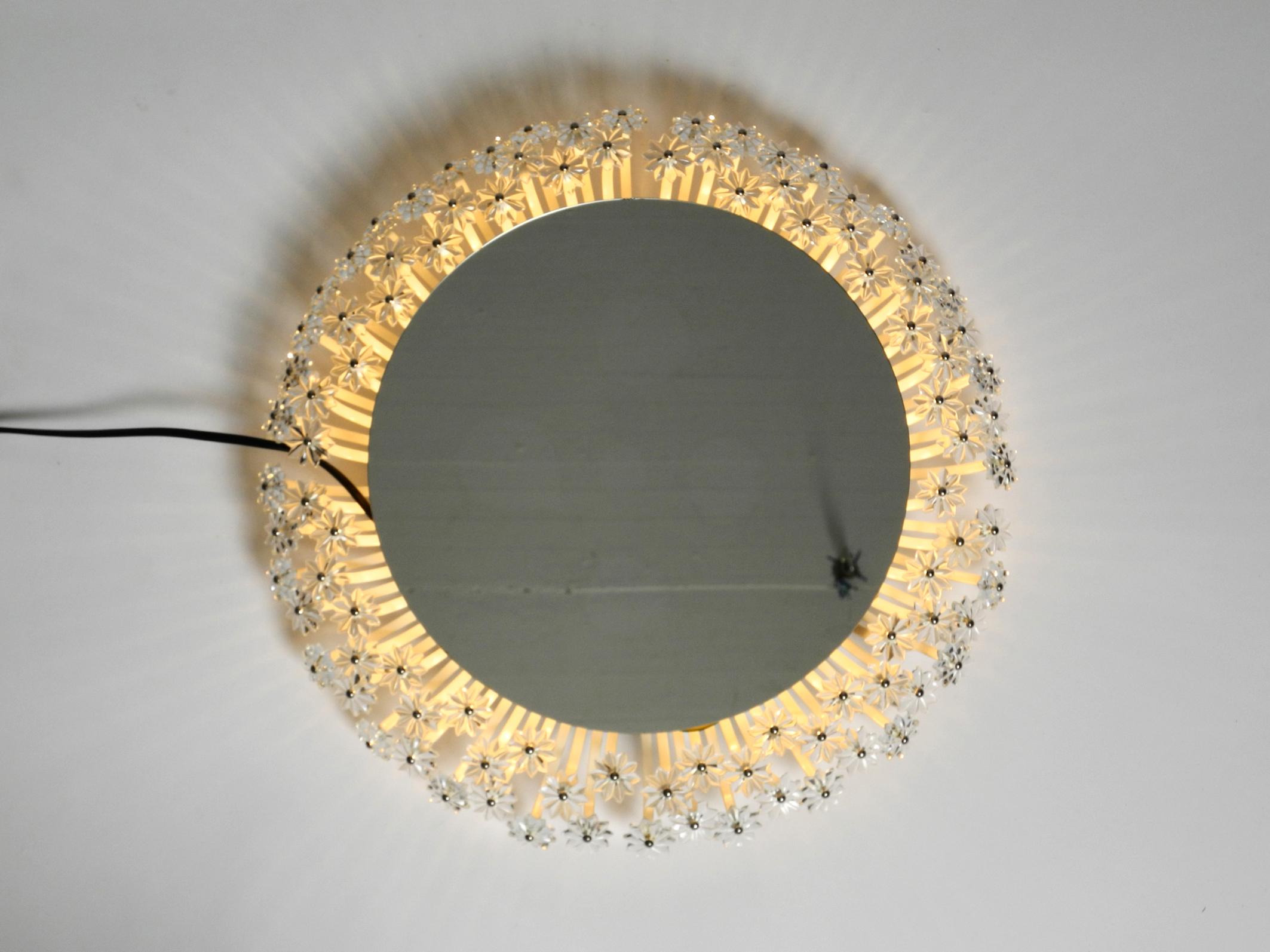 Beautiful rare background illuminated Mid-Century Modern mirror by Münchener Zierform. Manufacturer is Schöninger.
Great elaborate design with lots of small plastic flowers.
It is illuminated from the back with an E27 bulb with a maximum of