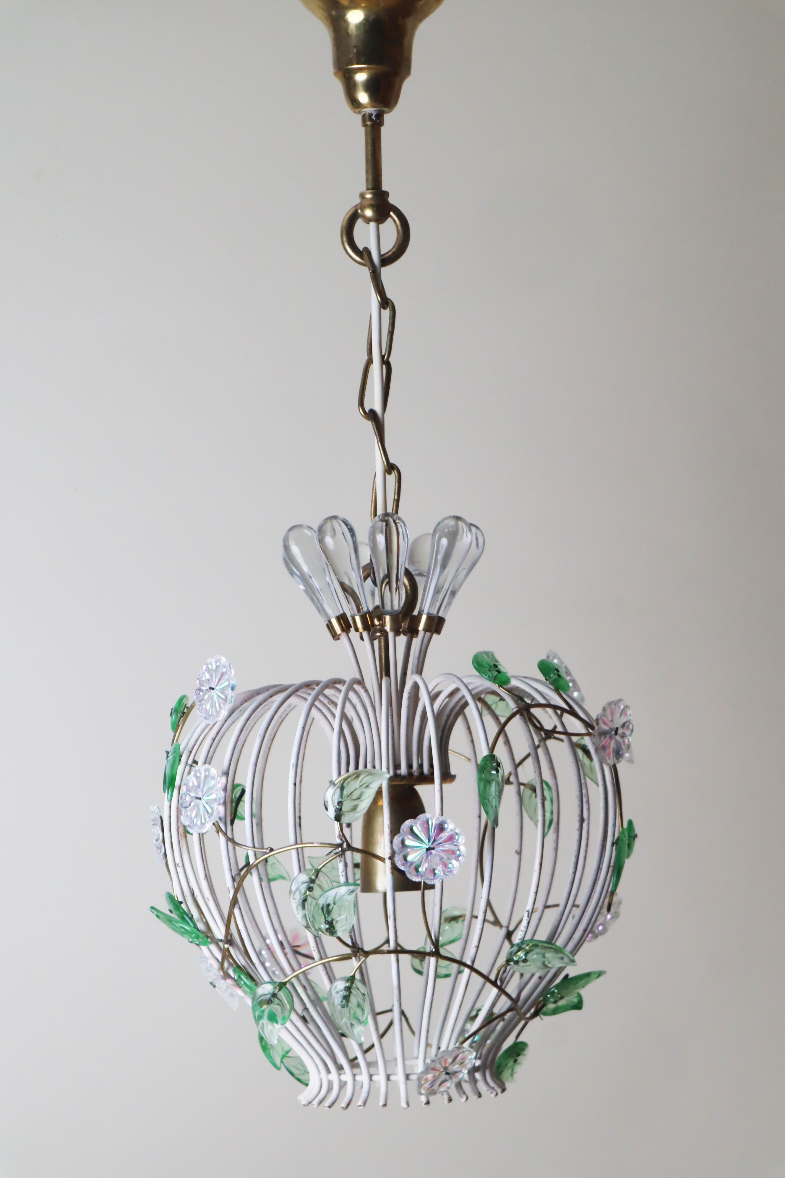 Sono davvero entusiasta di mostrarti questa splendida lampada a sospensione con un design a gabbia di uccello assolutamente affascinante! È decorato con graziosi fiori di vetro colorati e foglie verdi che riflettono il verde della natura. Permettimi