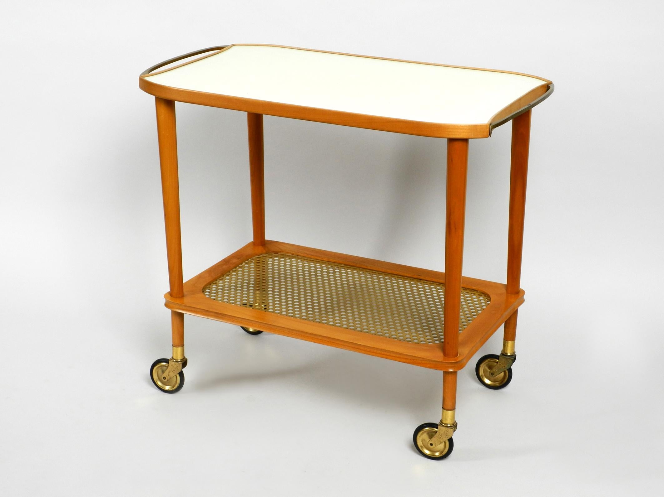 Very rare beautiful Mid-Century Modern serving cart made of solid walnut wood.
From a German or Austrian production.
Lower perforated metal shelf and handles are made of brass.
Shelf is made of light beige Formica.
The serving trolley is in good