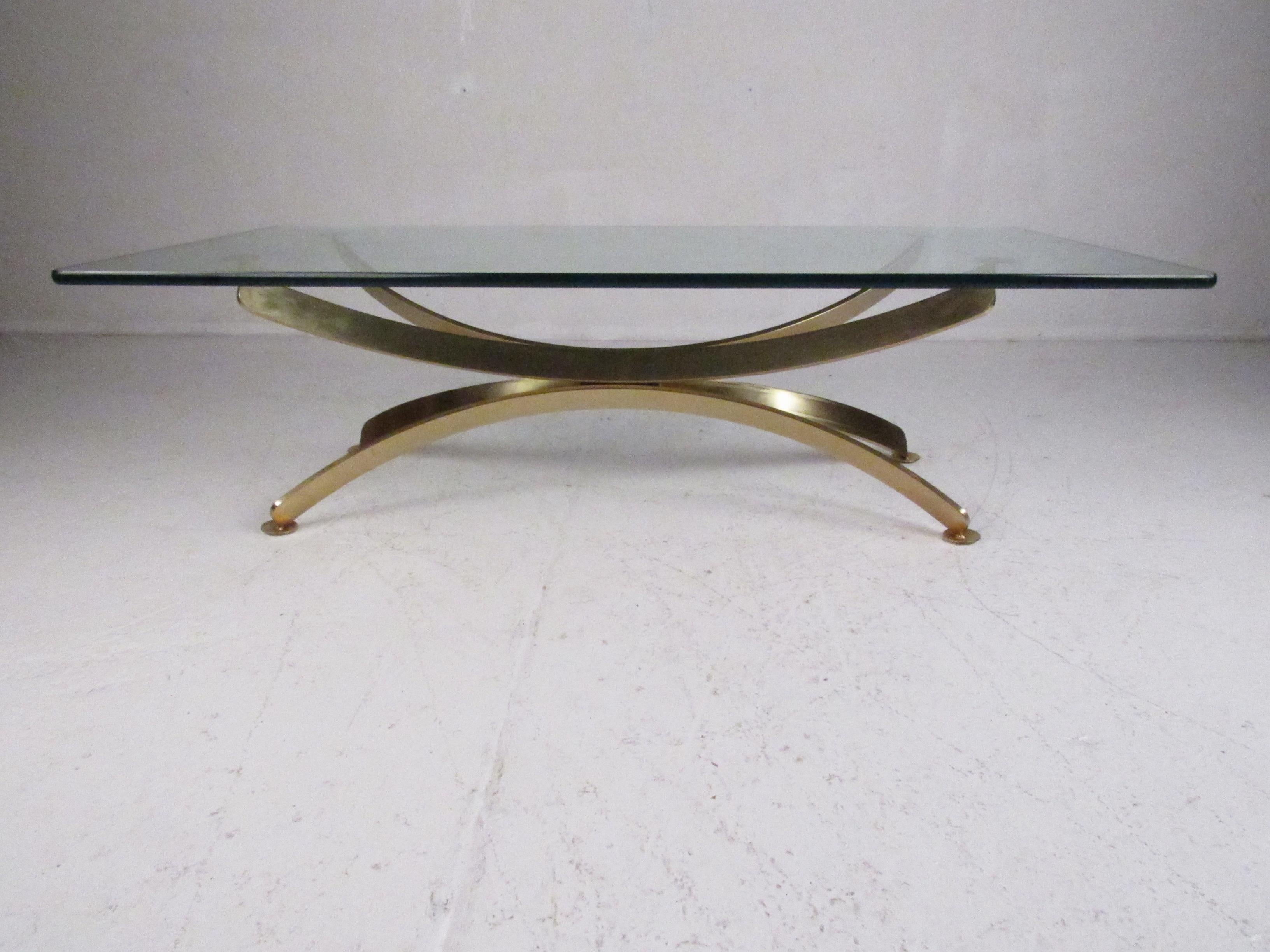 An elegant vintage modern coffee table with an extremely heavy brass base. This unique table features a bent flat bar base and a massive rectangular glass top. A sleek design that is sure to make a lasting impression in any home, business, or