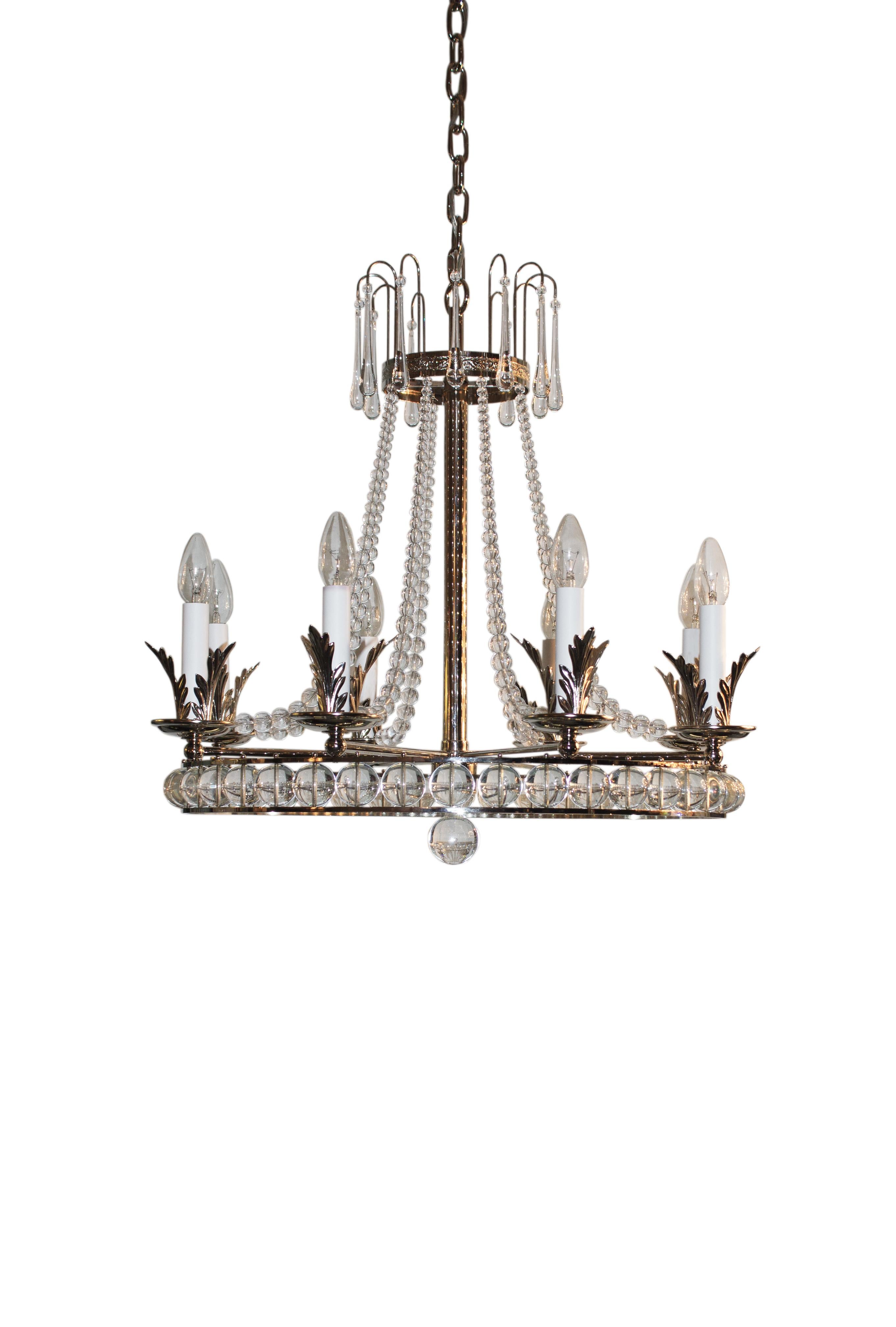 This polsihed and nickel finished chandelier is studded with glass spheres that are fully hand cutted and glass drops. Further the metal leaves make the design a very special but still simplified light. The colour gives any room a warm light but is