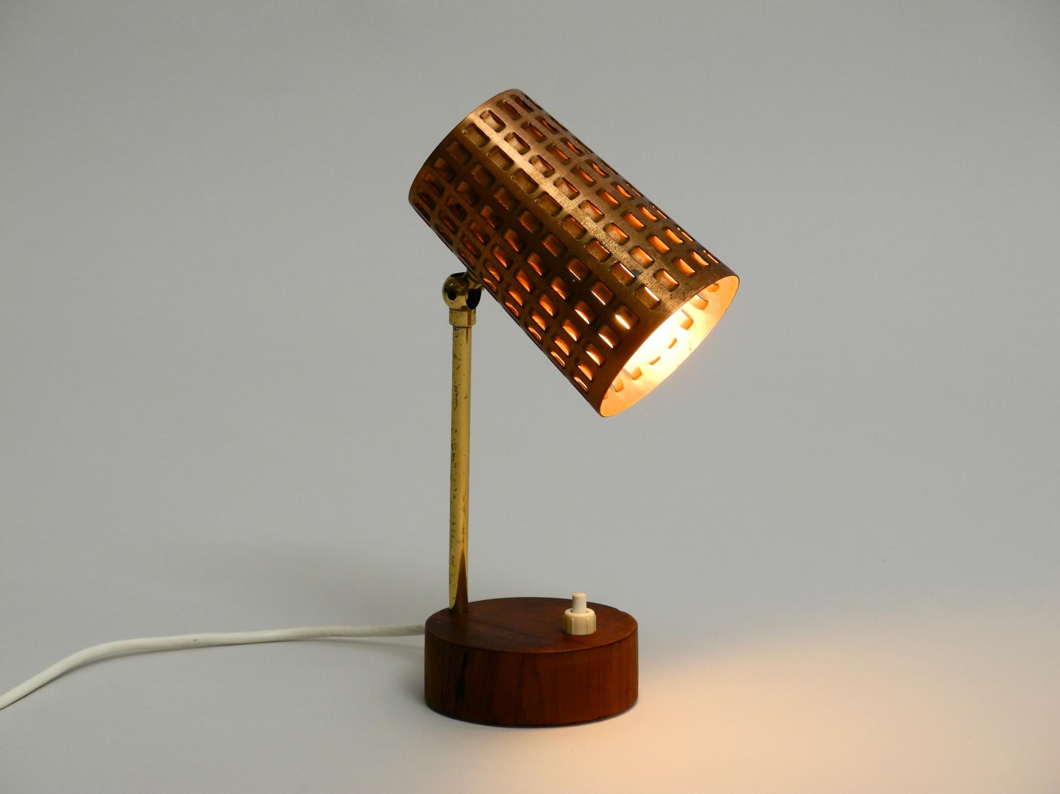Rare very nice midcentury table or night lamp
with perforated metal shade made of copper. 
Neck is made of brass. Base is with teak verneer.
Very nice design of the 1950s with great patina.
Shade is steplessly adjustable up and down.
100%