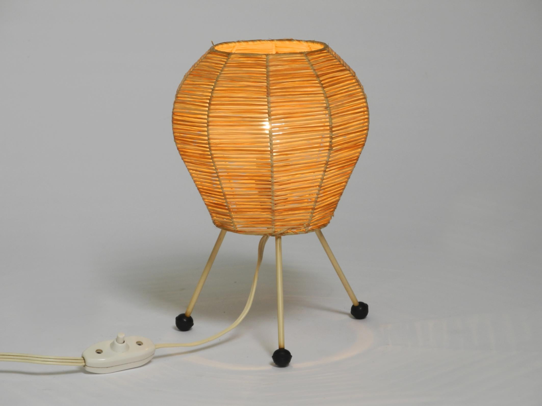Beautiful Mid Century Modern tripod raffia table or night lamp. Typical 1950s design.
Very good vintage condition and no damage to the metal frame and lampshade.
Raffia weave is impeccable. Very clean and well-maintained condition. No tears or