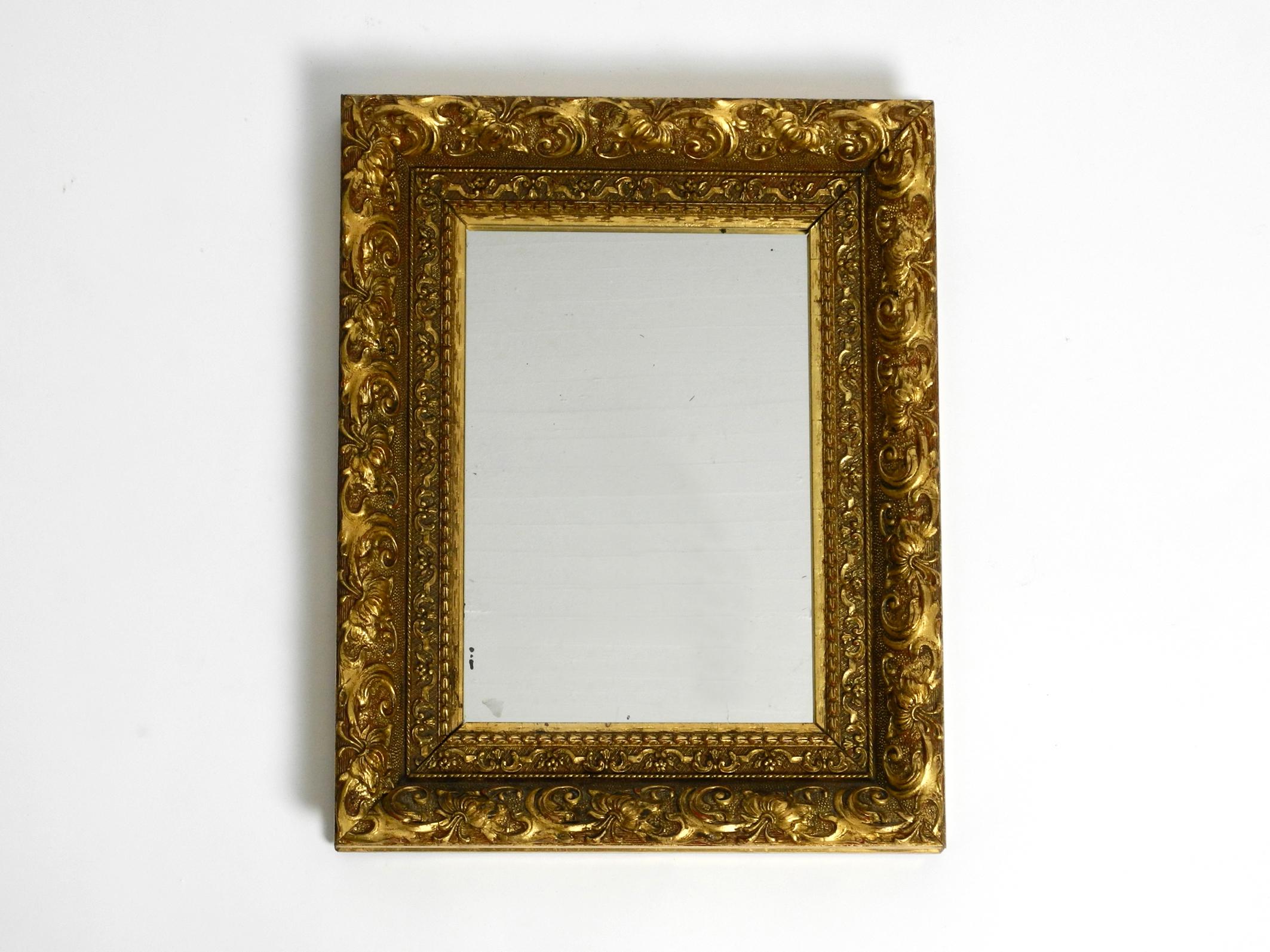 Beautiful rare Mid Century wall mirror made of ornate solid wood.
The frame is completely gold-plated and has a wonderful patina.
Manufactured in Italy in the 1950s.
Original mirror glass with a few black spots, but not blind.
Without damages to
