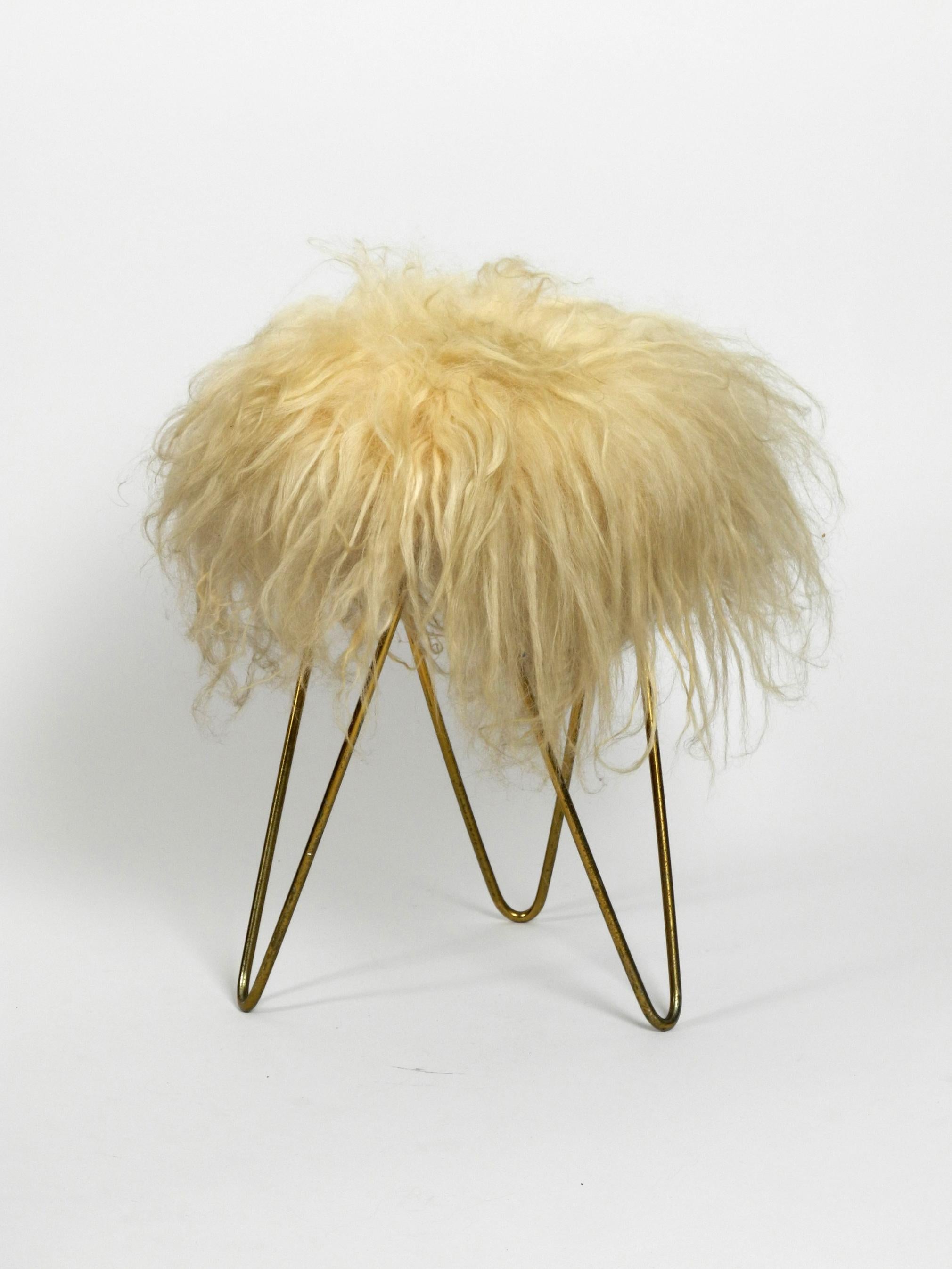 Beautiful midcentury white flokati stool with goat hair
cover and tripod hairpin feet.
The flokati cover is clean and not damaged, is firm and does not smell
Feet are made of brass anodized metal with nice patina.
No damages, not