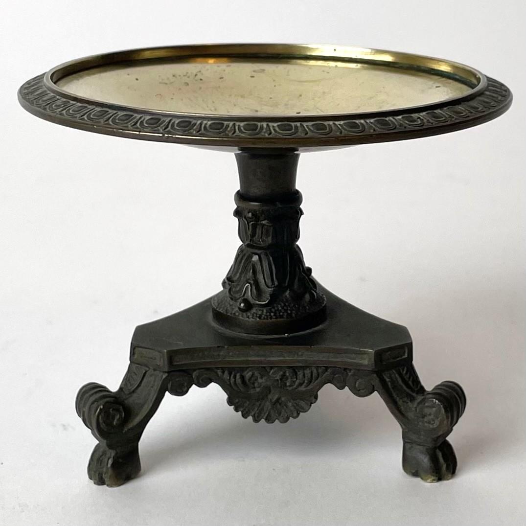 Ein schöner Miniatur-Tisch aus vergoldeter und patinierter Bronze. Hergestellt in Frankreich,
1830s-1840s.

Alters- und gebrauchsbedingte Abnutzungserscheinungen.