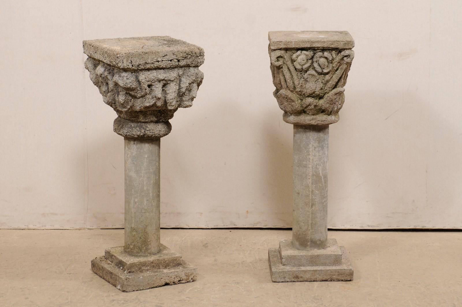 A Spanish pair of mismatched, cast-stone garden pedestals from the mid 20th century. This pair of vintage pedestals from Spain stand just shy of 3 feet in height. Each has a similar yet different design, featuring ornately decorated tops (one in a