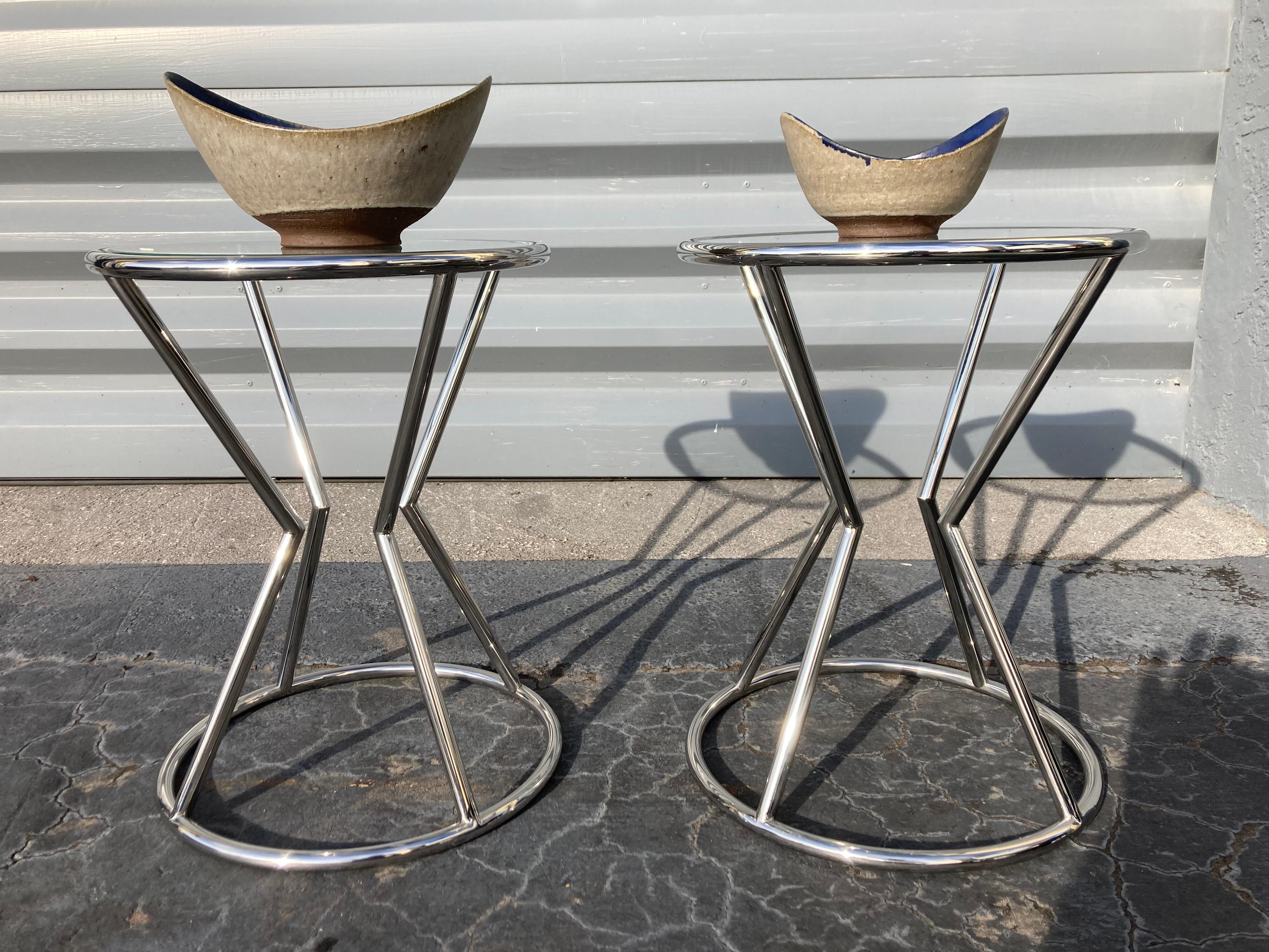 Pair of stainless steel side tables with glass tops.