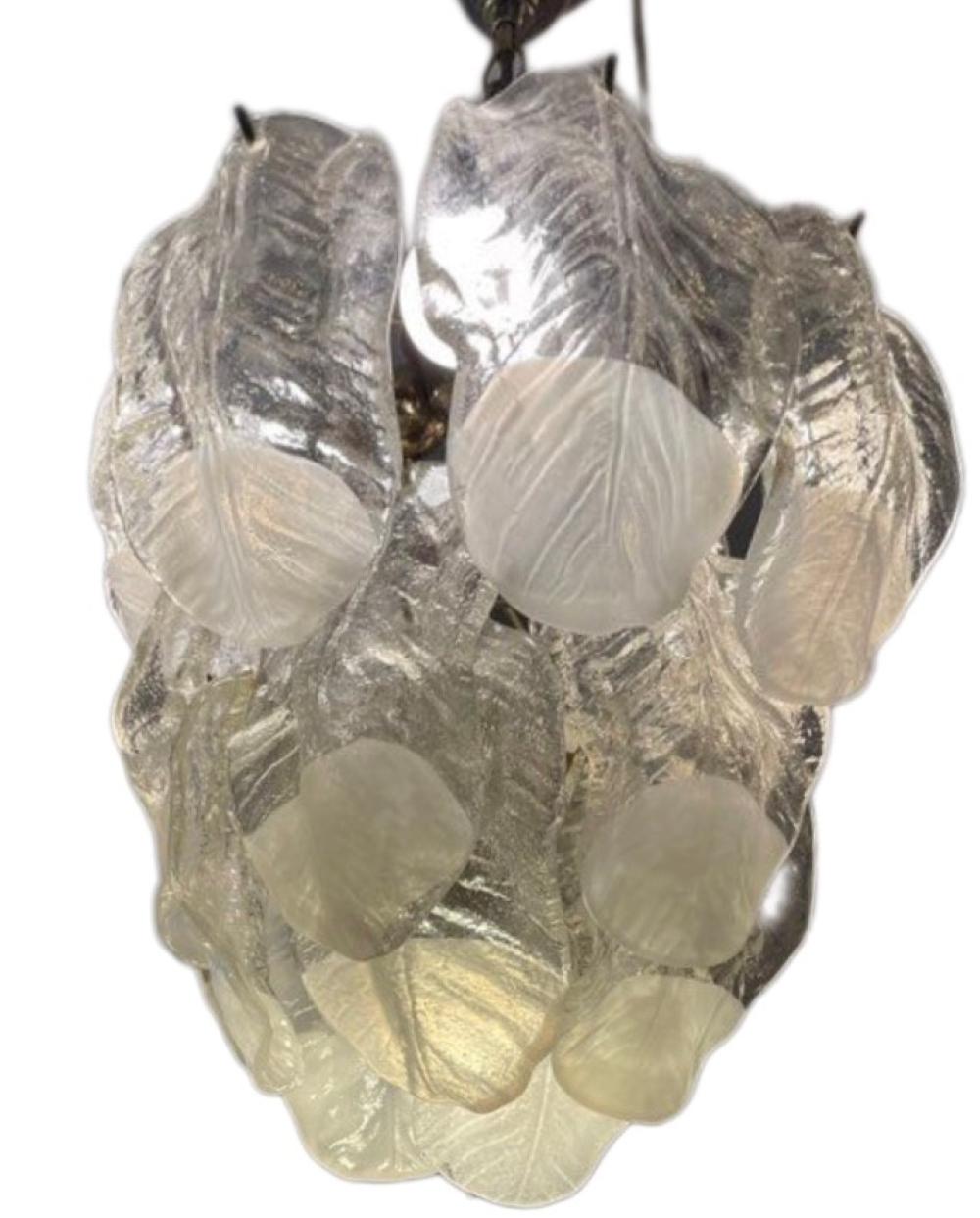 Superb Murano glass chandelier. The glass is cut by hand in the shape of leaves.
The chandelier consists of a golden metal structure and 24 sheets of translucent and pearly Murano glass. To the touch the leaves are smooth on the outside and granite